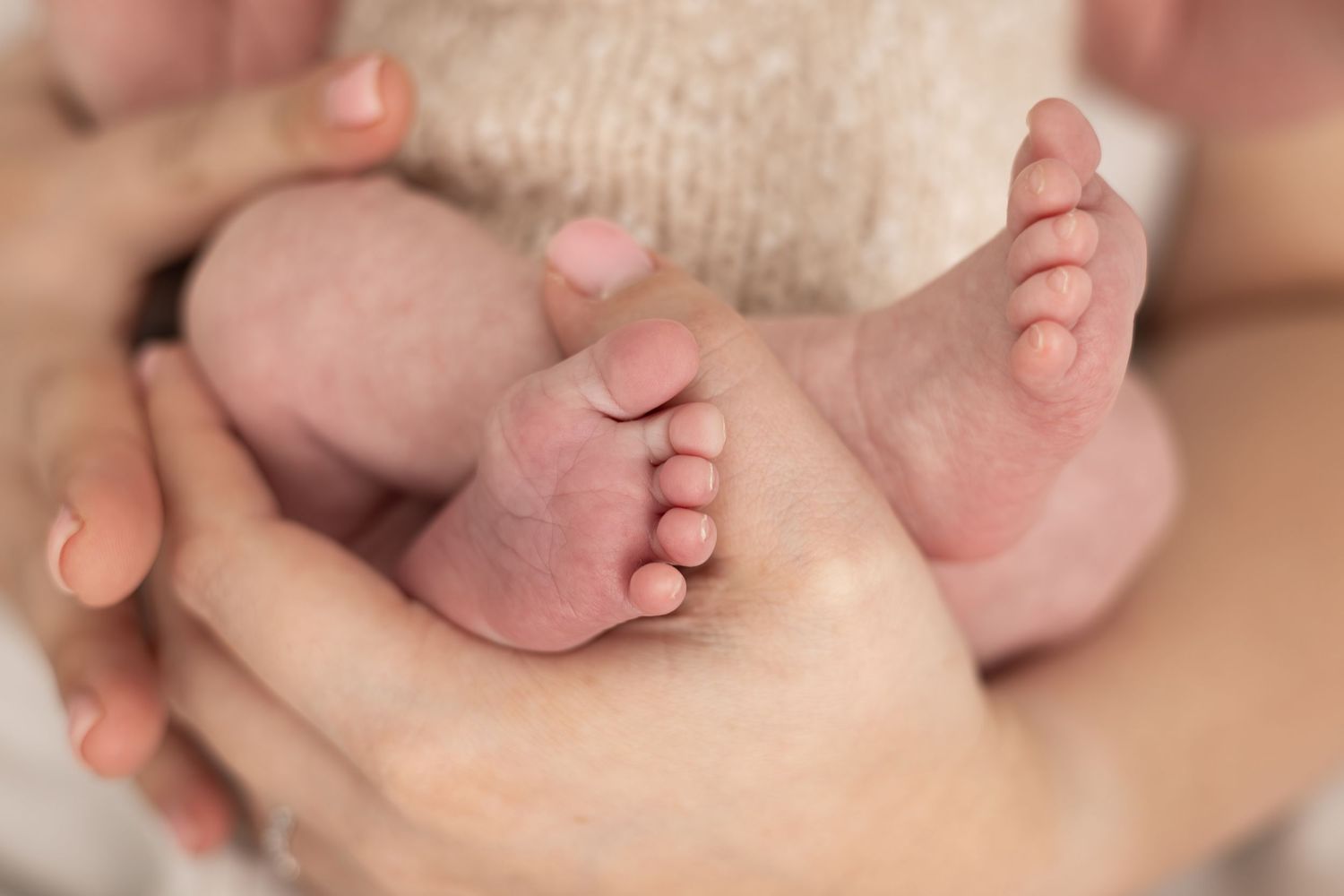 Close-up of tiny baby feet being gently held in adult hands.