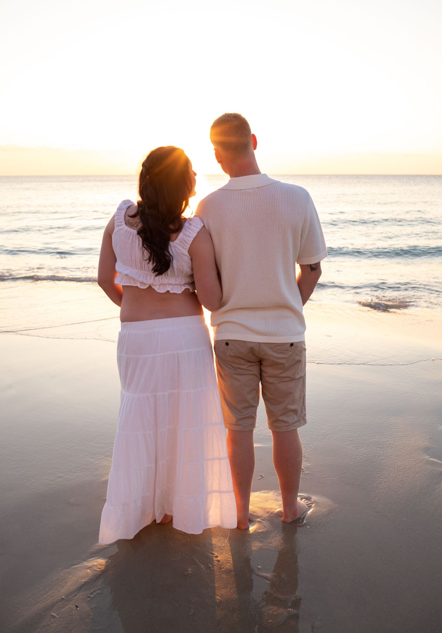 Couple watching sunset during intimate maternity photoshoot.
