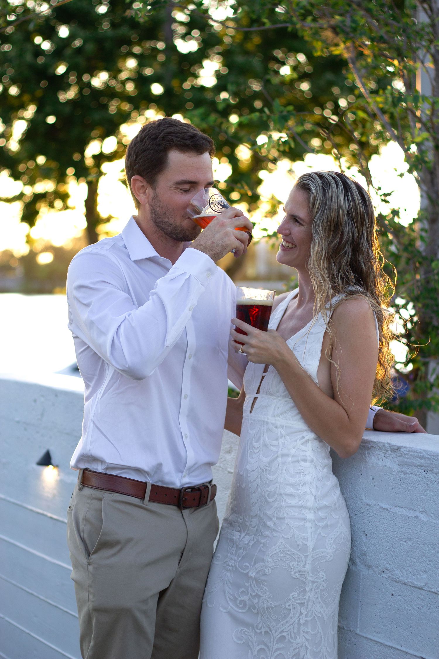 Couple enjoying drinks and romance against white wall with bokeh lighting.