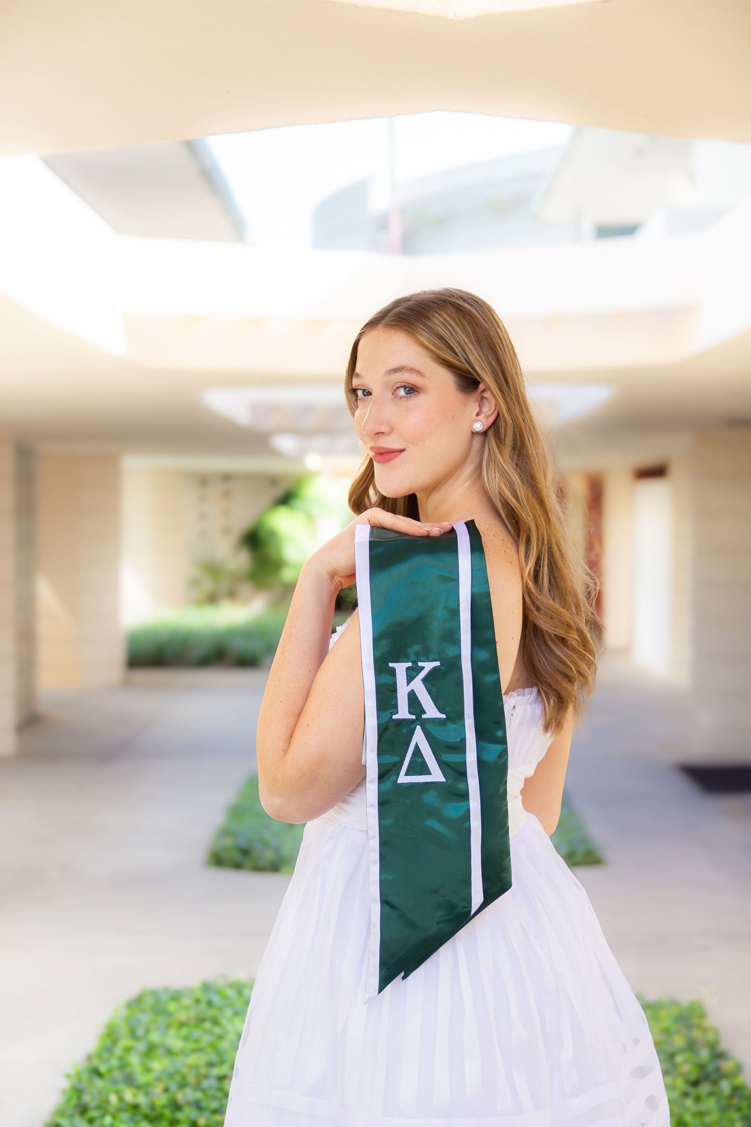 A series of four photos showing a person in a white dress holding up a green banner with a letter K.