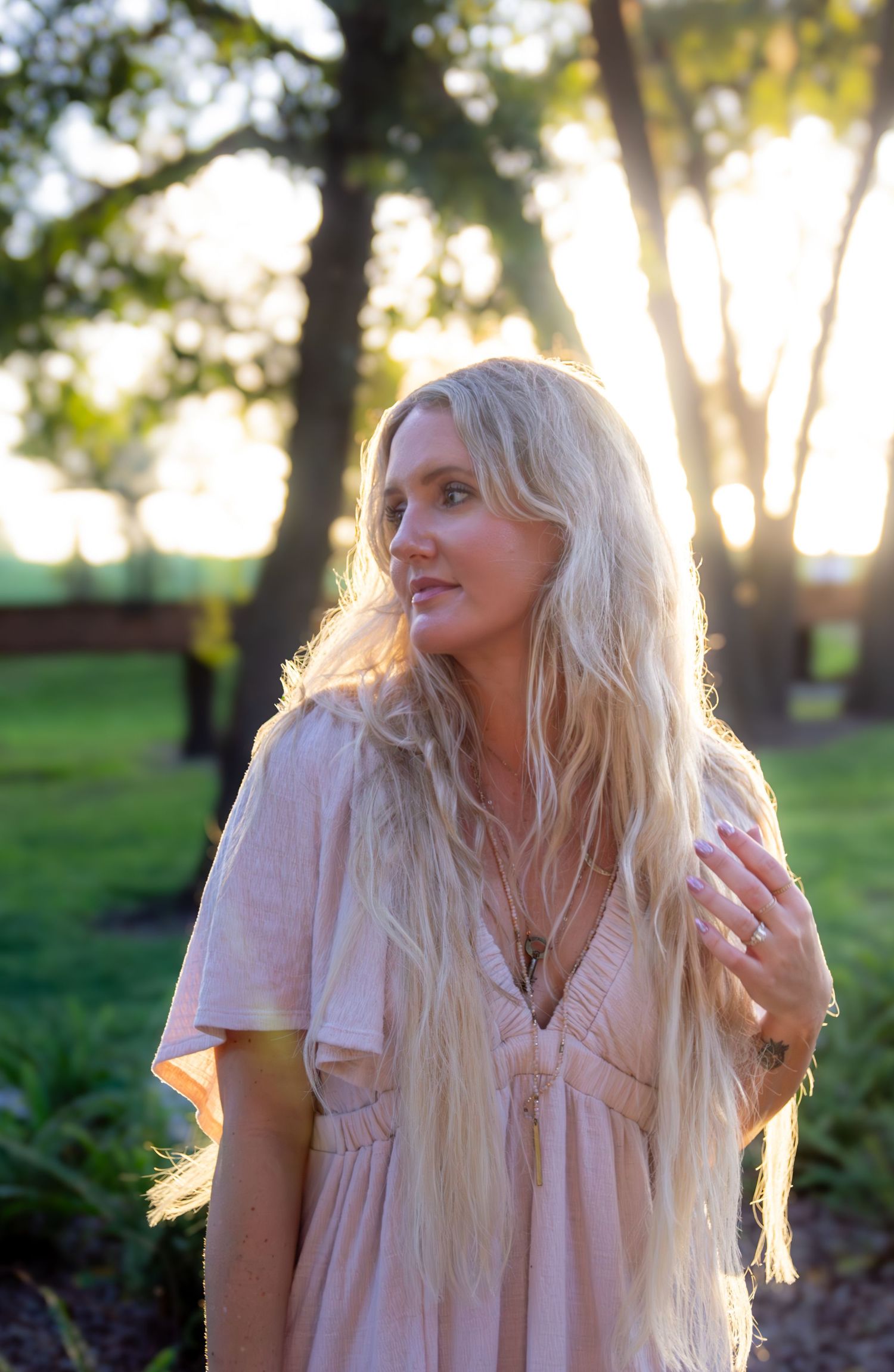 A series of four photos showing someone with long blonde hair wearing a light pink dress in an outdoor setting at sunset.