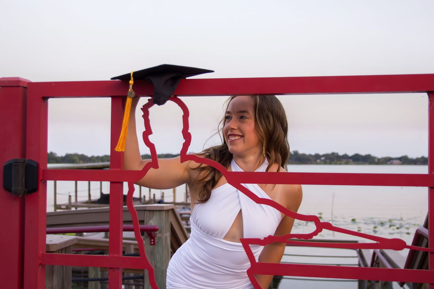 Graduate posing with red wall backdrop at Florida Southern campus.