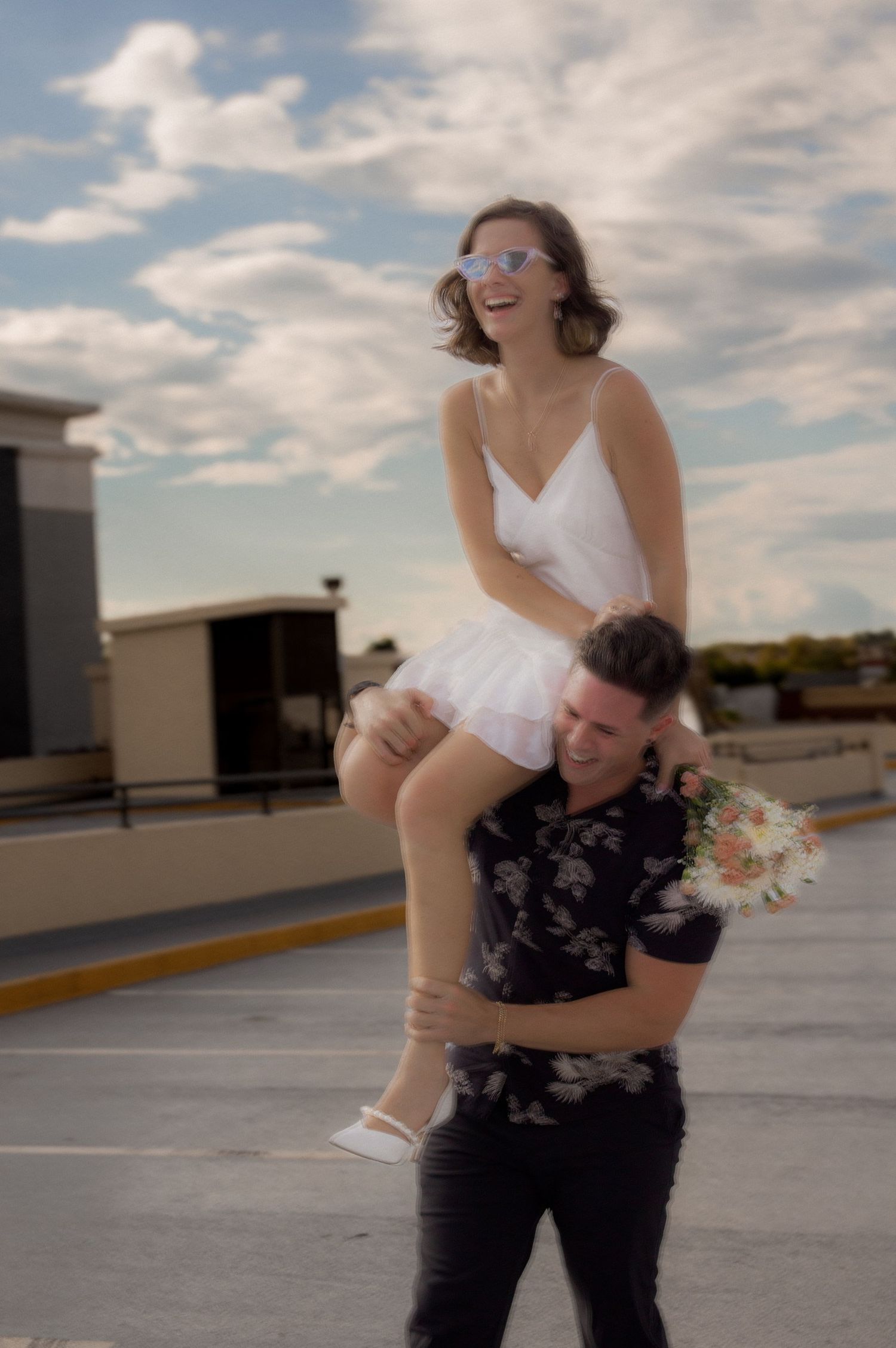 Playful piggyback ride on rooftop parking lot under cloudy sky.