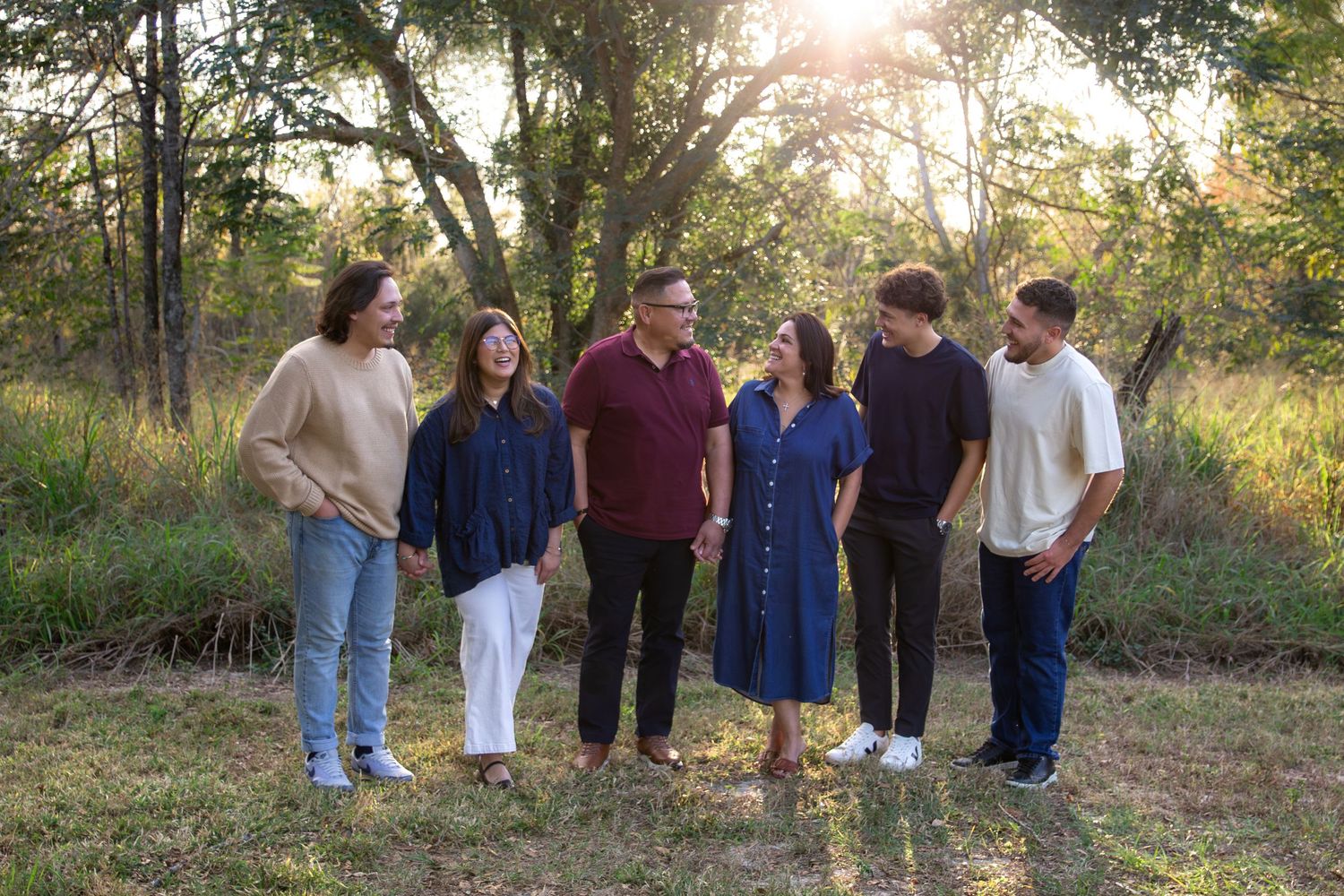 Group of people walking together on a dirt path through a wooded area during golden hour sunlight.