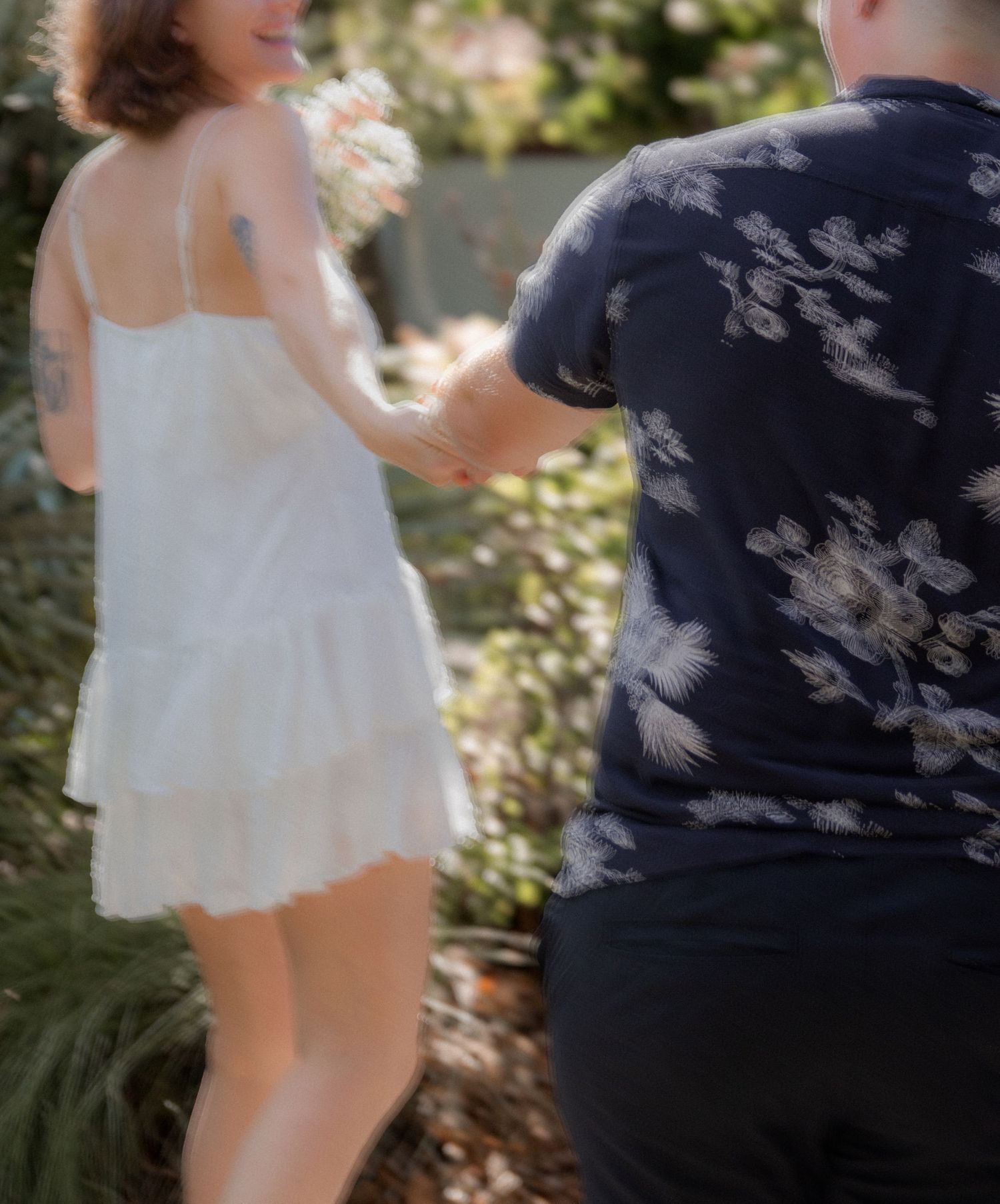 Couple in white dress and dark shirt share playful moment outdoors.