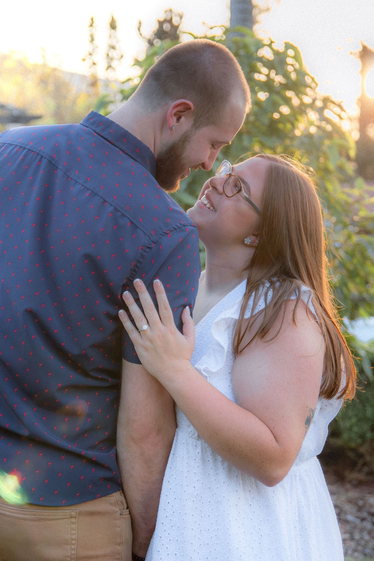 A couple shares an intimate moment during a romantic sunset engagement photo session.