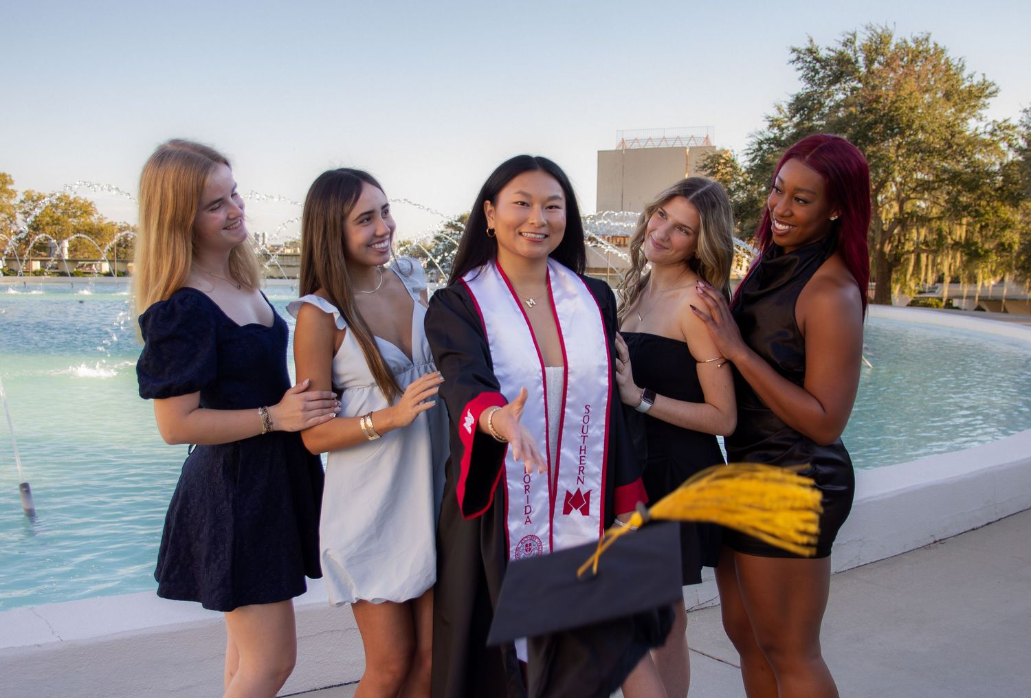 A group of friends laughing and embracing while enjoying a sunny day outdoors together.