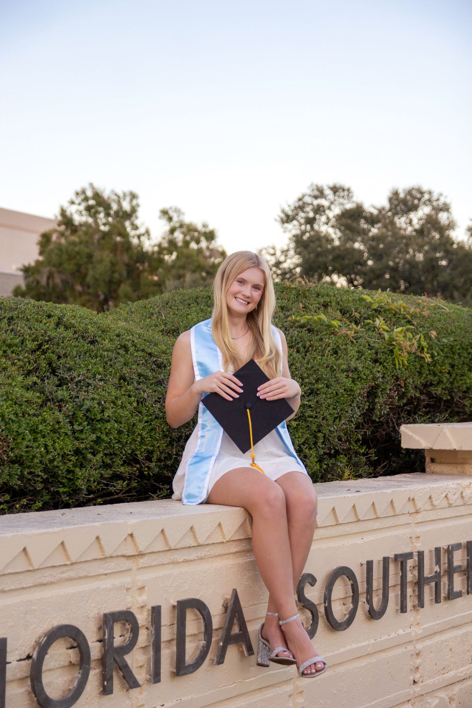 A student sits on a concrete wall with text reading 'Florida South' in an outdoor campus setting.