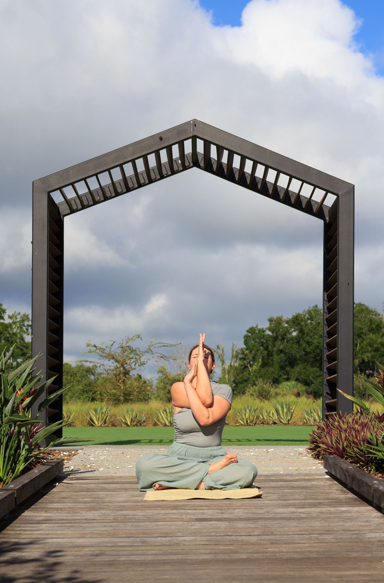 A sequence of yoga poses performed on a wooden deck with architectural framing and cloudy sky in the background.