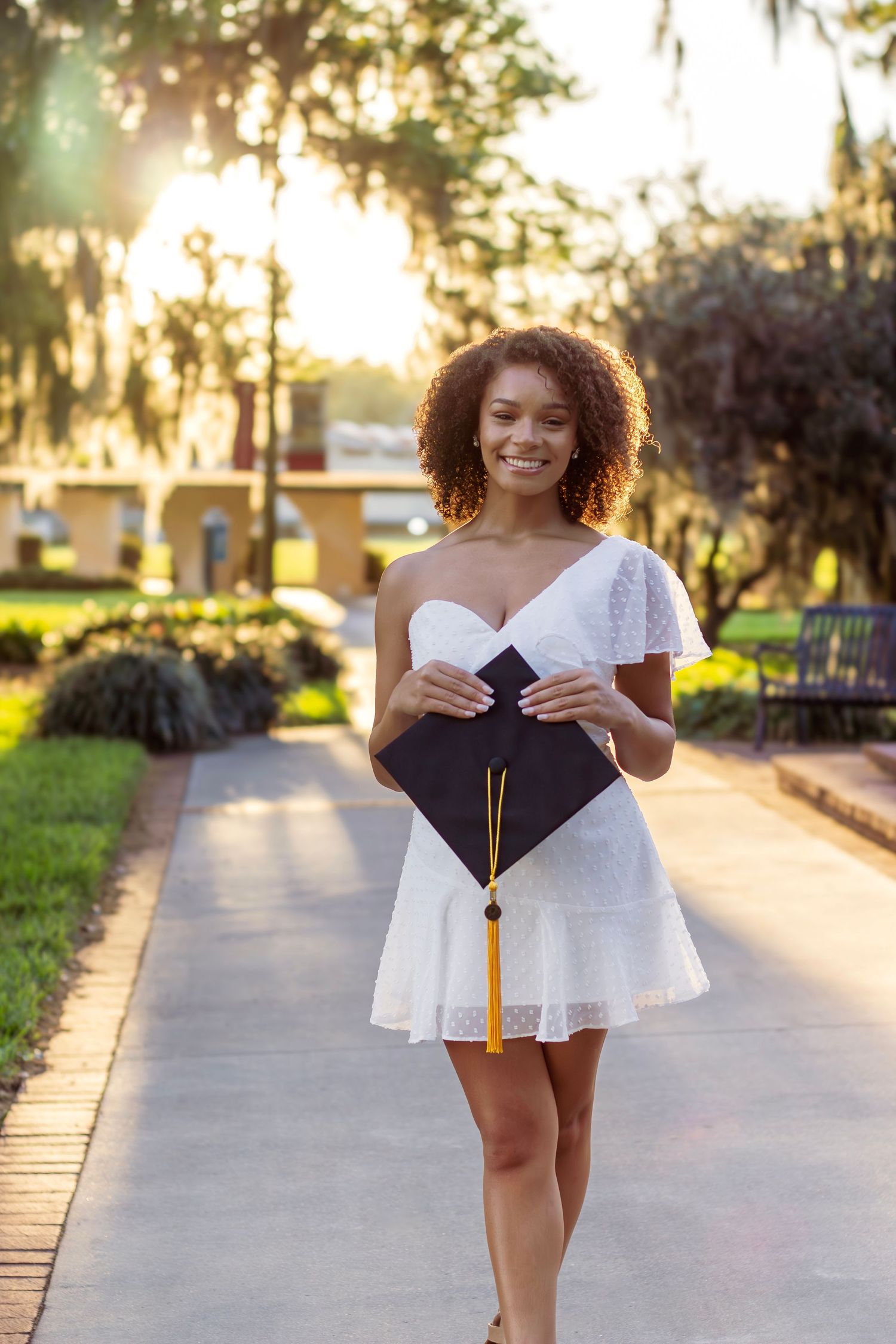 Four connected photos show a person in white and black outfits posing on a sunlit path with trees in the background.