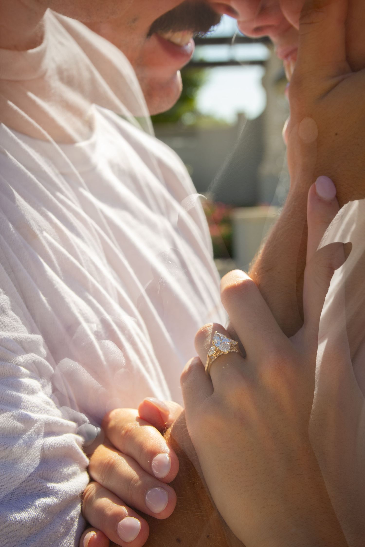 Close-up of a couple sharing a romantic moment, woman wearing a large diamond engagement ring.