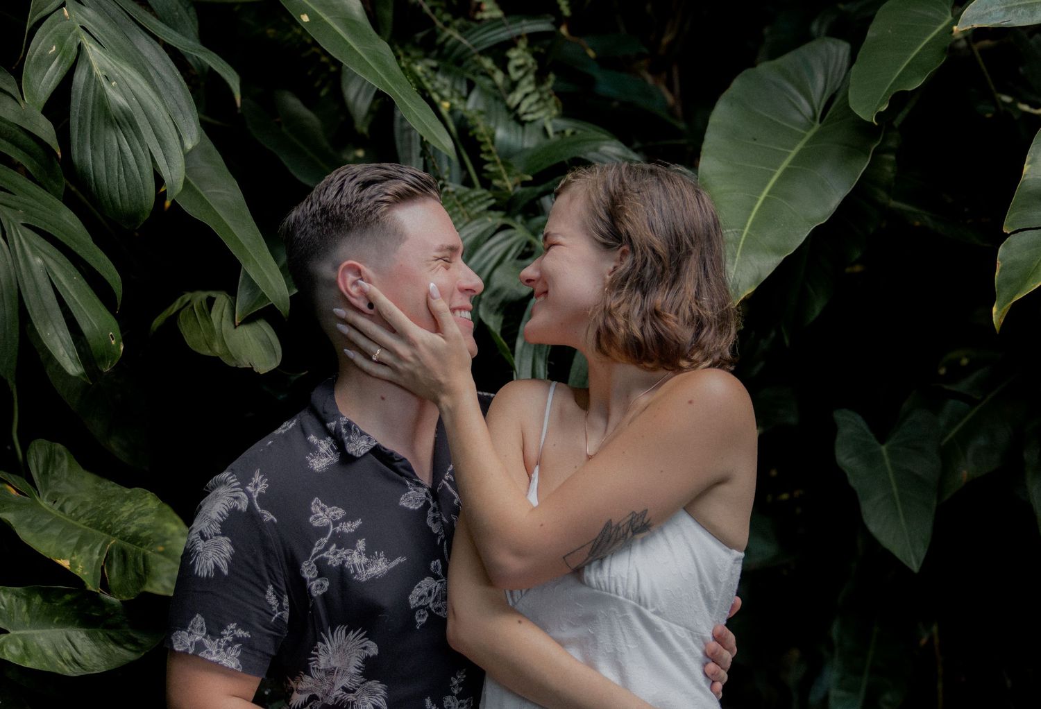 Romantic couple embracing outdoors in a lush garden setting.