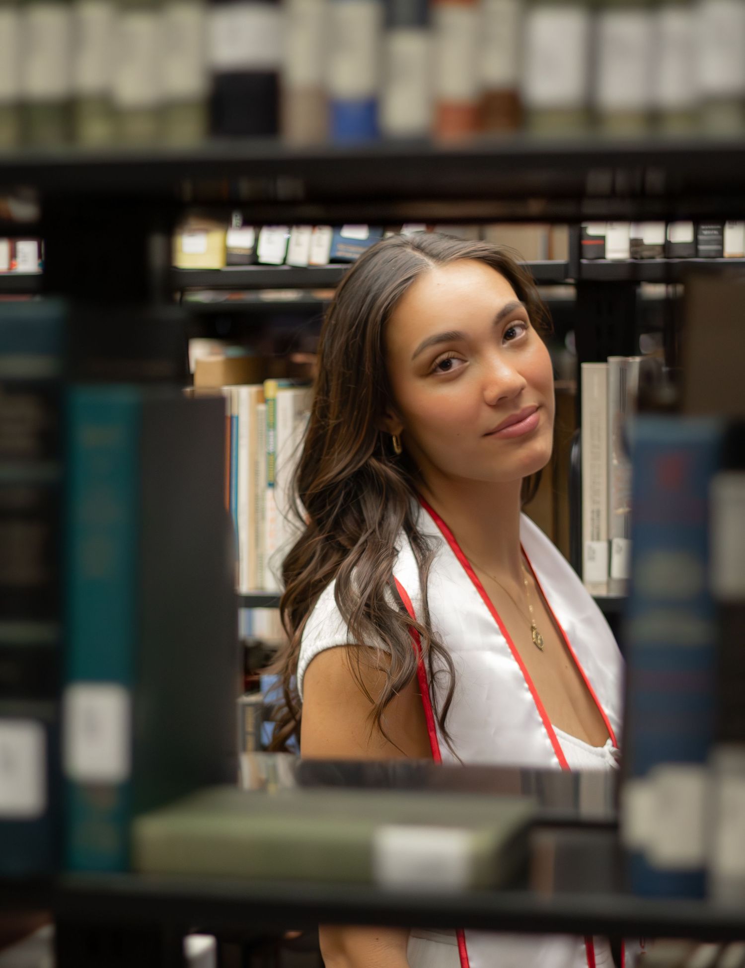 Graduate portrait series taken between library bookshelves.