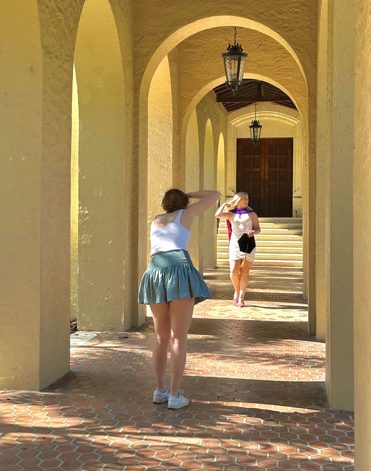 Yellow archways and columns create a repeating architectural pattern on a brick walkway.