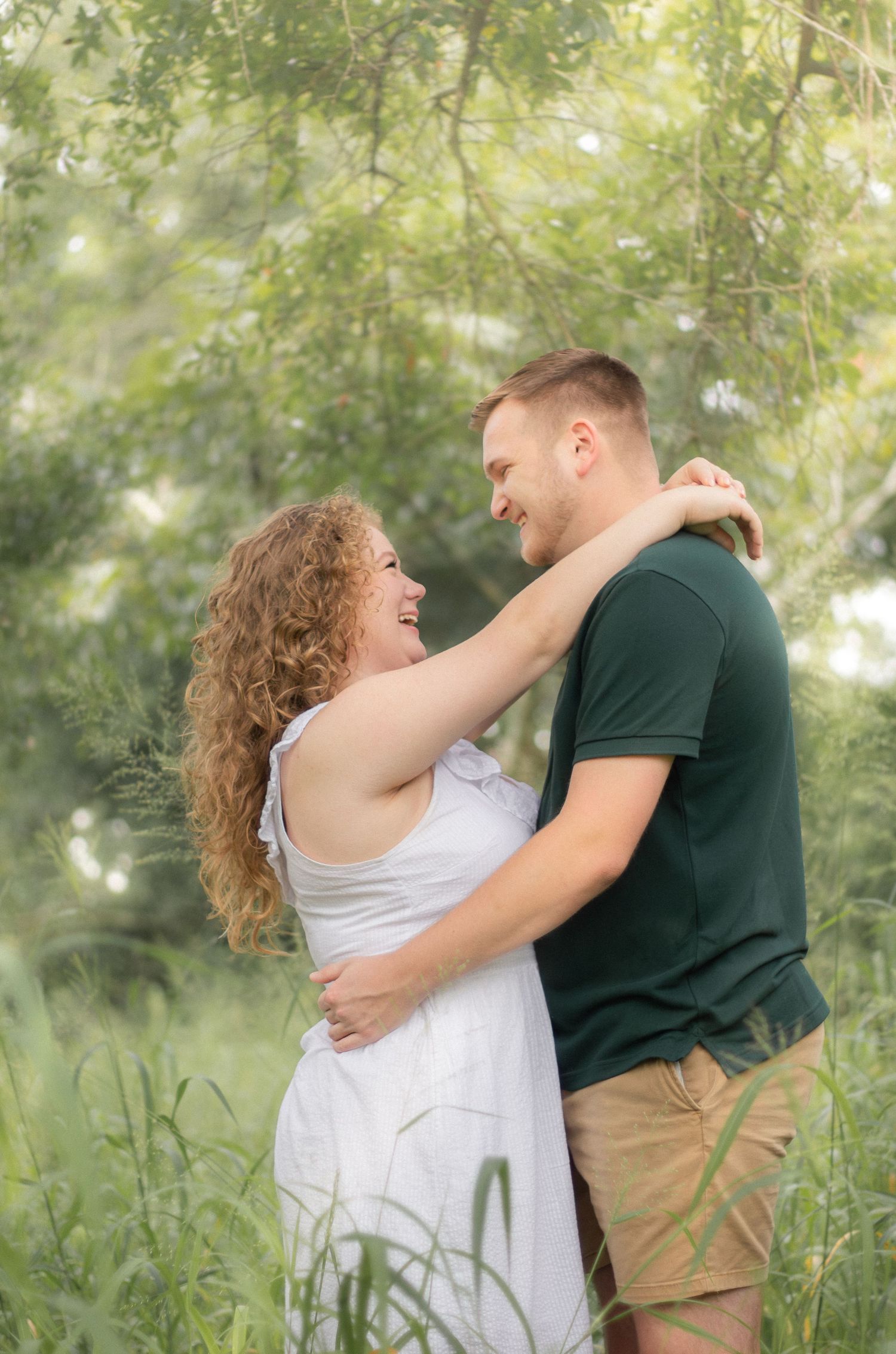 Happy couple embracing in sunlit garden with natural greenery backdrop.