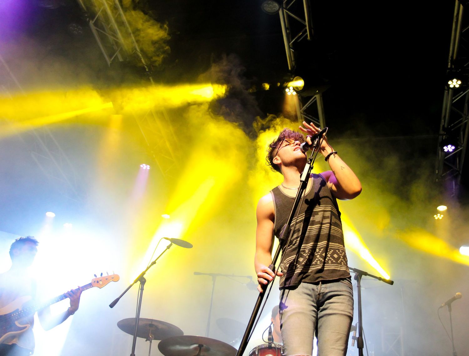 Concert performers on stage bathed in dramatic yellow lighting during an energetic live music performance.
