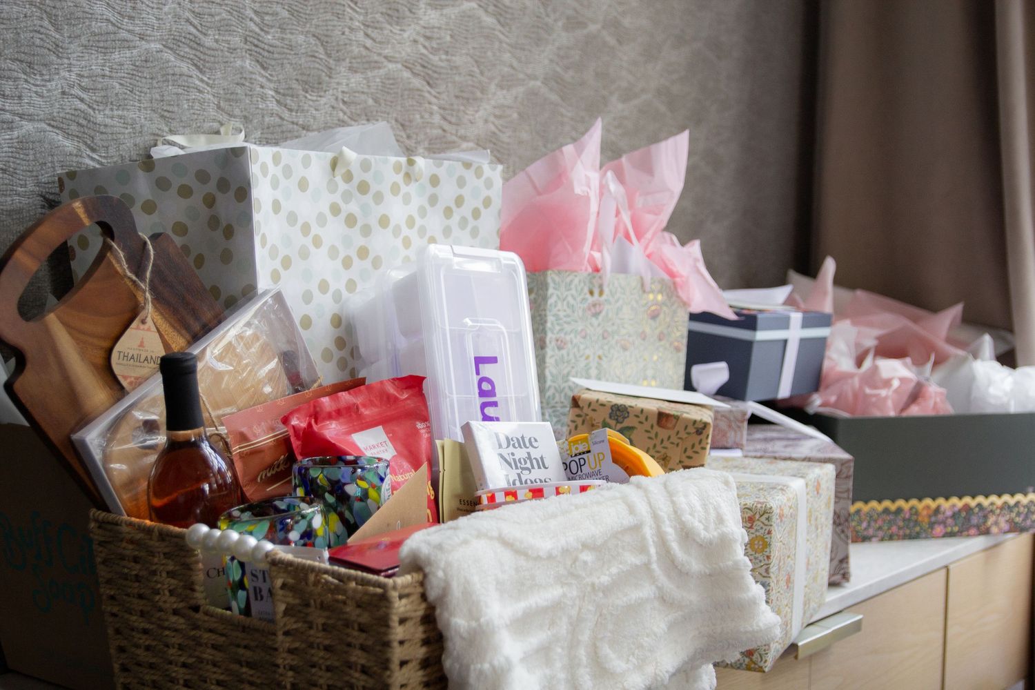 A collection of wrapped gifts and presents overflowing from a woven basket with polka dot patterns and tissue paper.
