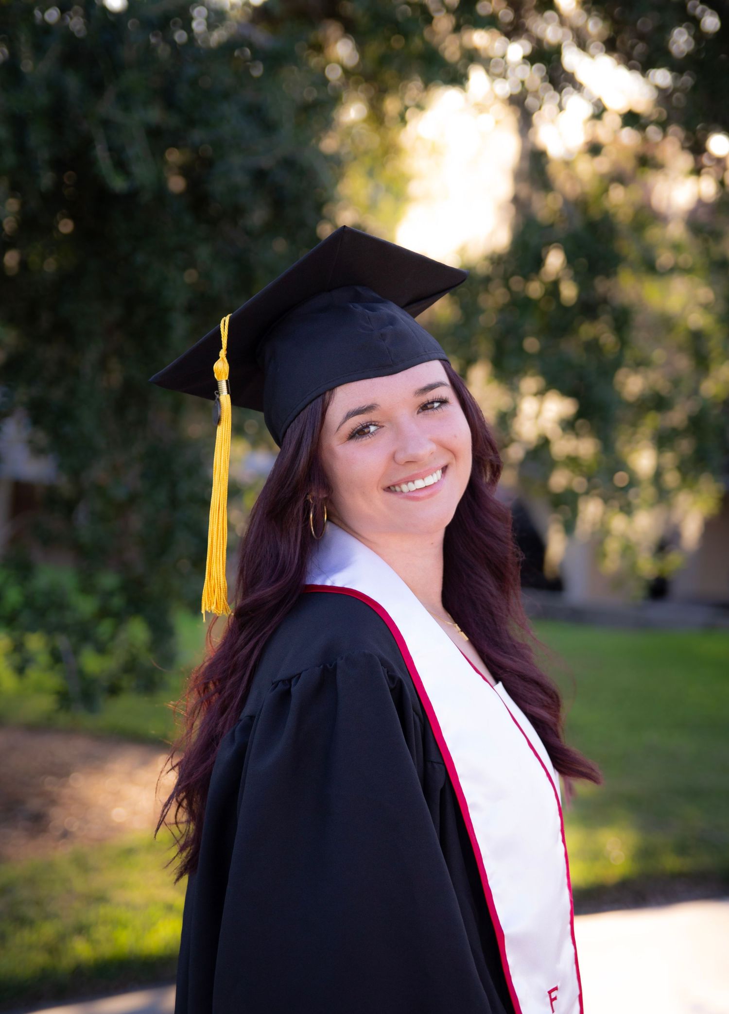 Graduate in cap and gown poses outdoors during golden hour with joyful expressions in a series of photos.