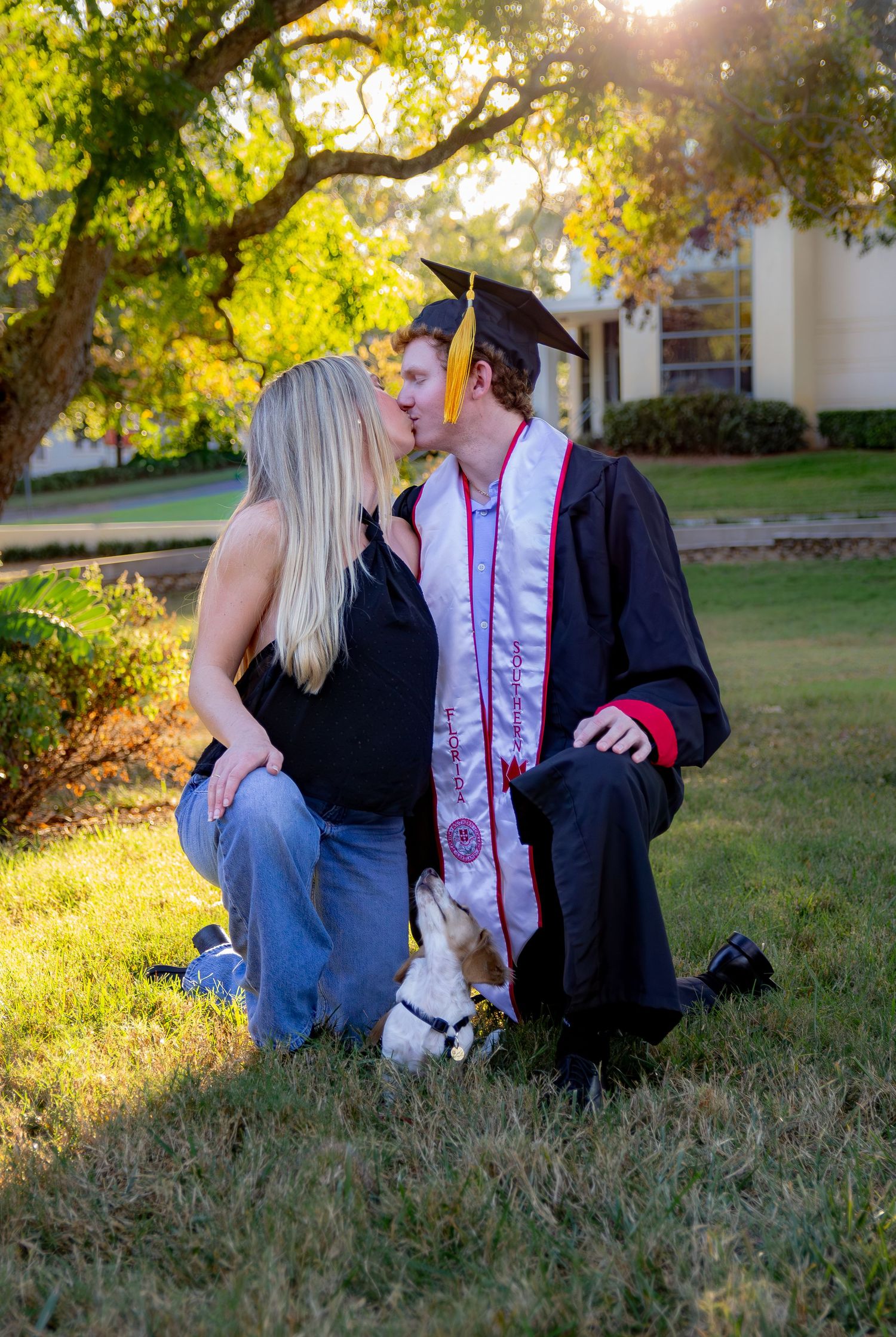 A couple shares an intimate moment sitting together on grass during golden hour sunset.