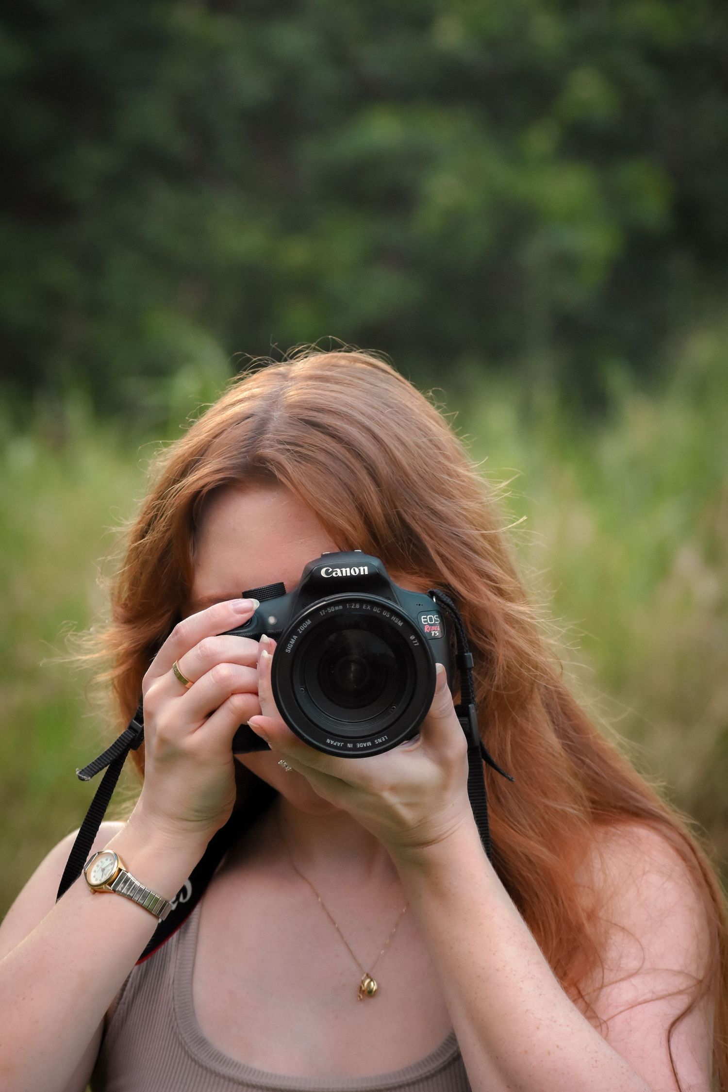Photographer with Canon DSLR camera taking photos in a natural outdoor setting.