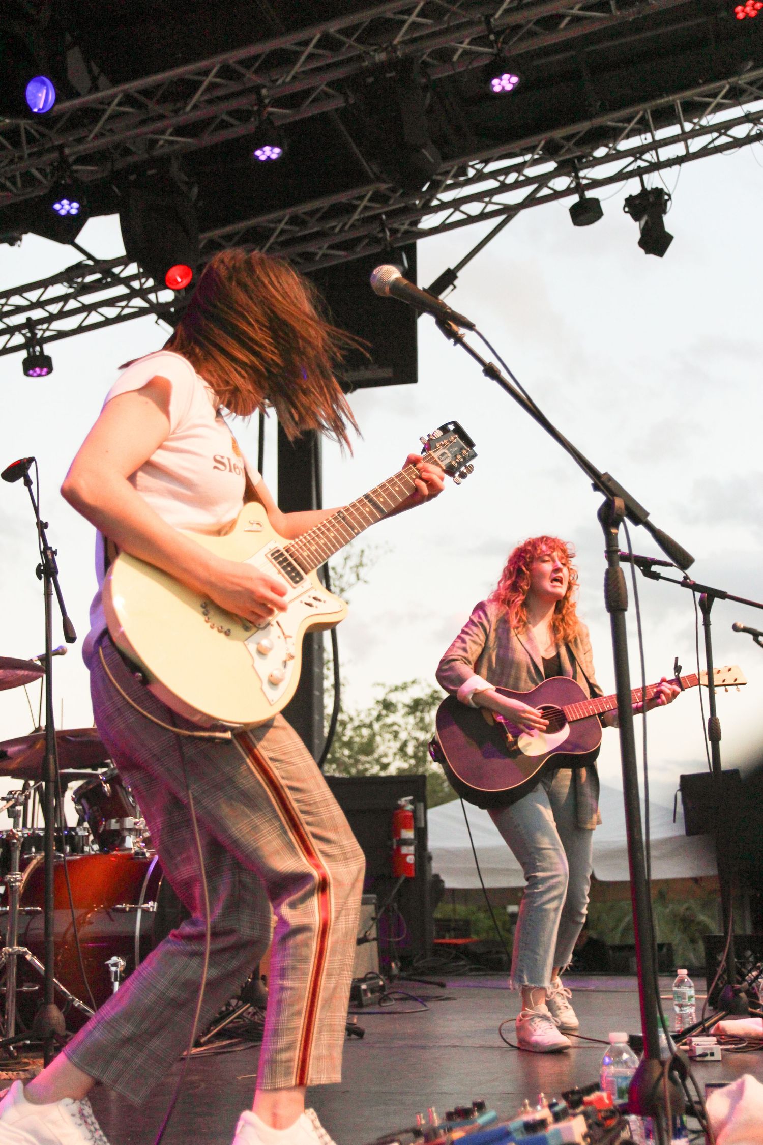 Energetic musicians perform on an outdoor festival stage with guitars and dynamic movement during a live show.