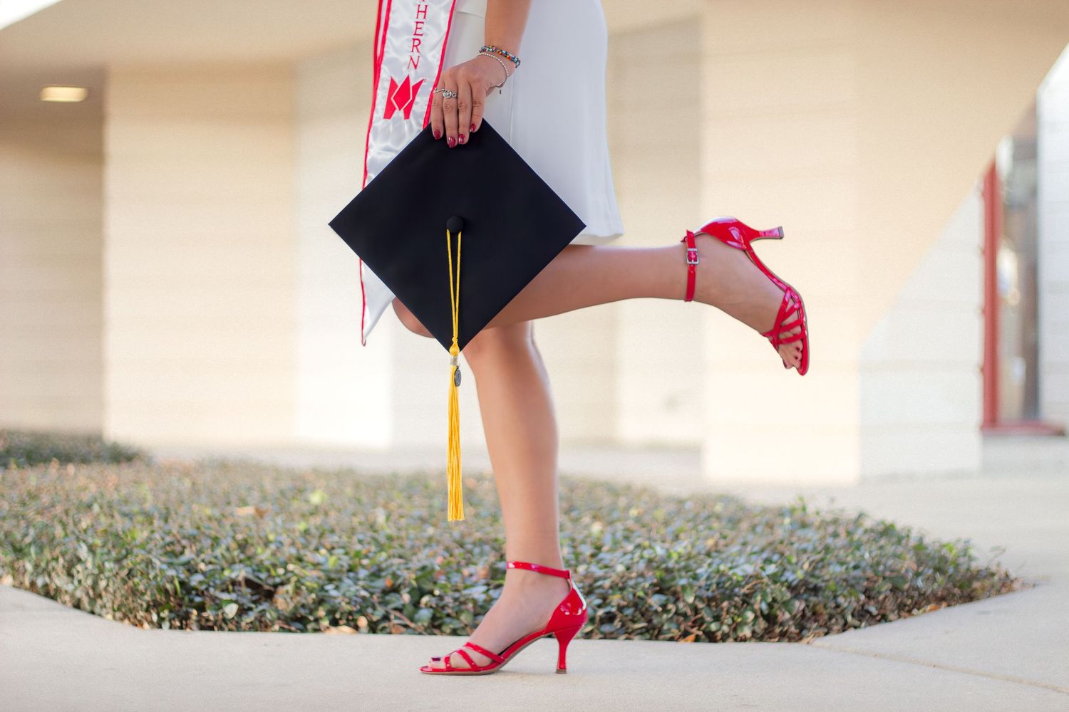 Graduation cap and red high heels shown in a creative photo collage against a neutral background.