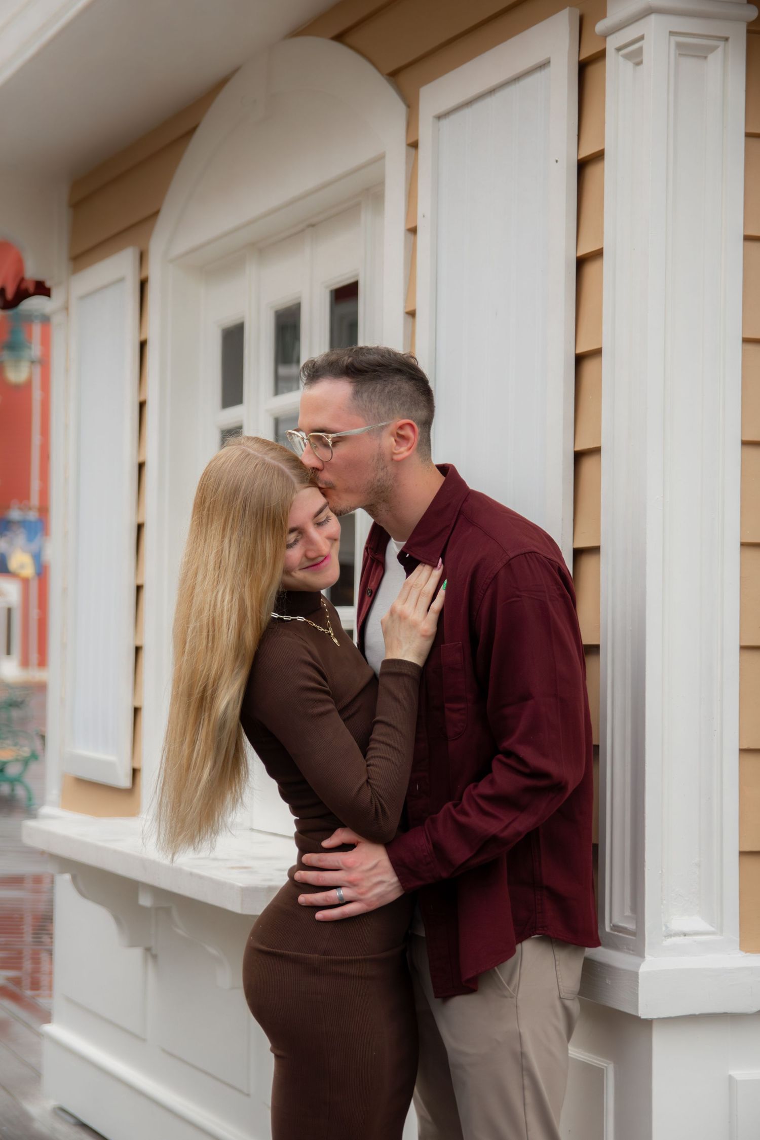 A couple shares intimate moments and embraces against a light-colored building exterior.