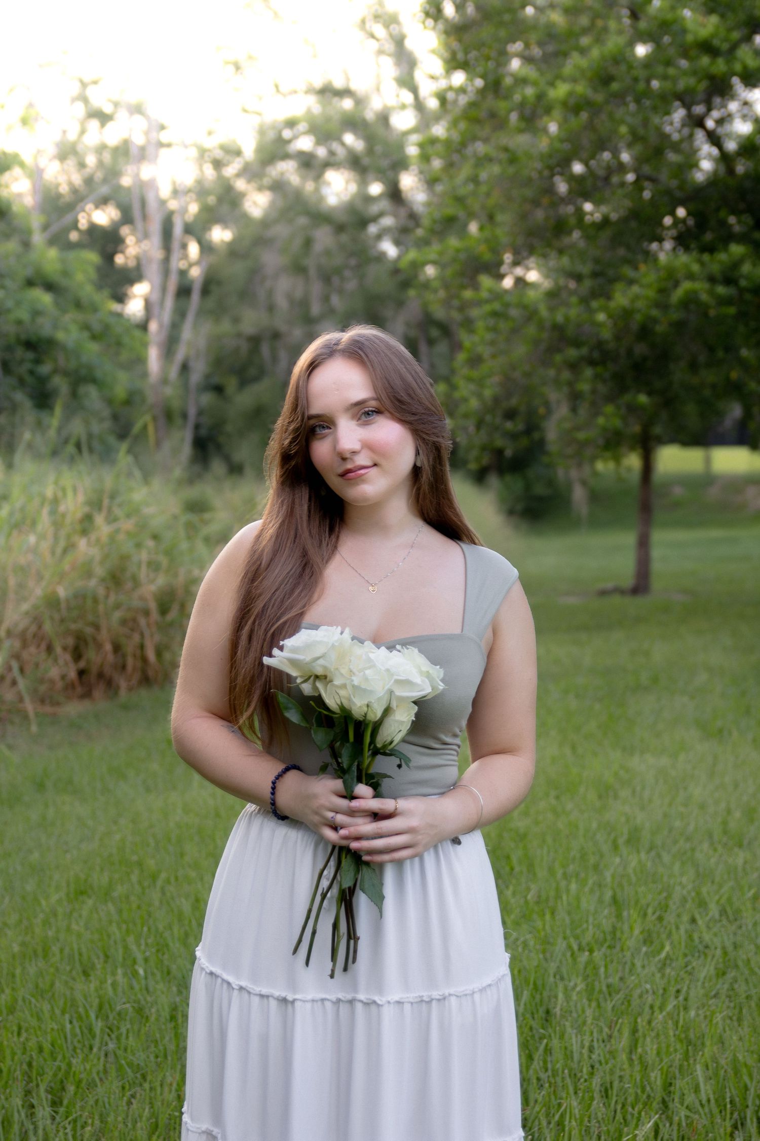 Portrait session in a grassy field with white dress and floral bouquet.