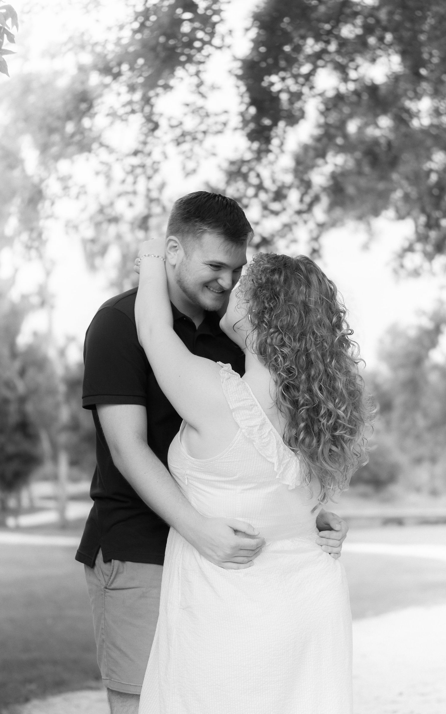 Black and white romantic portraits of a couple sharing intimate embraces outdoors.