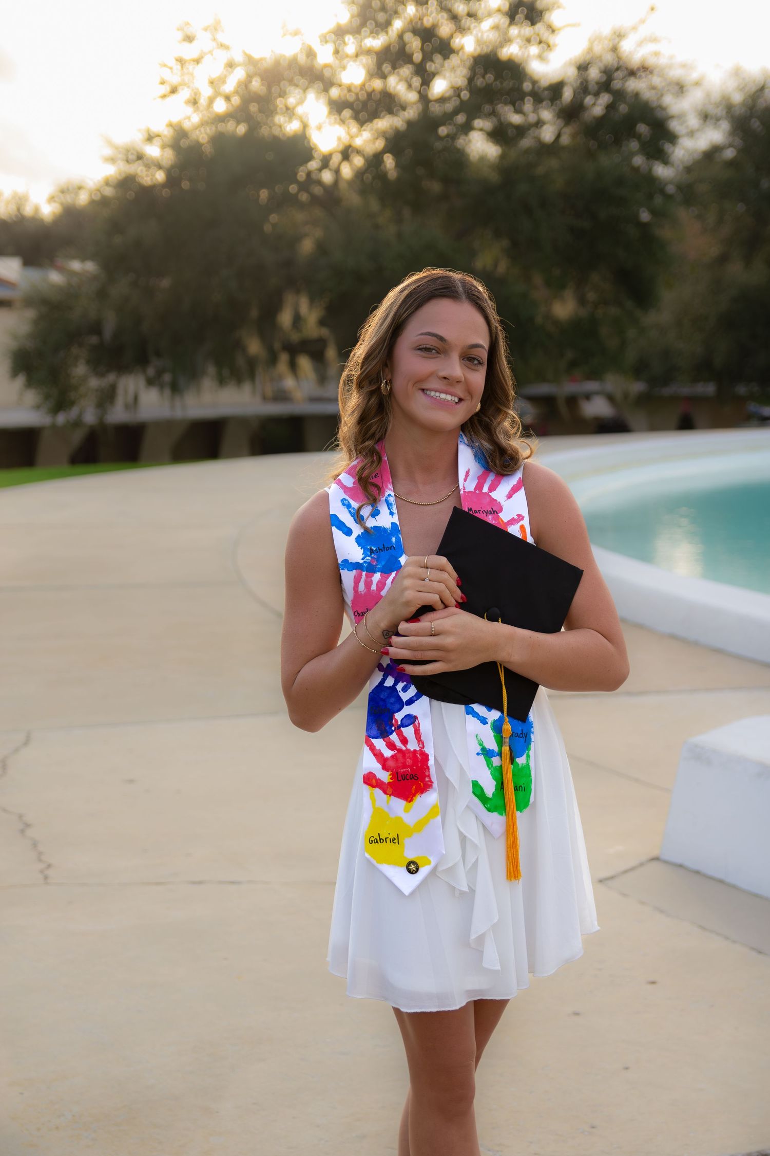 A series of photos showing a white dress decorated with colorful handprints in an outdoor setting at sunset.