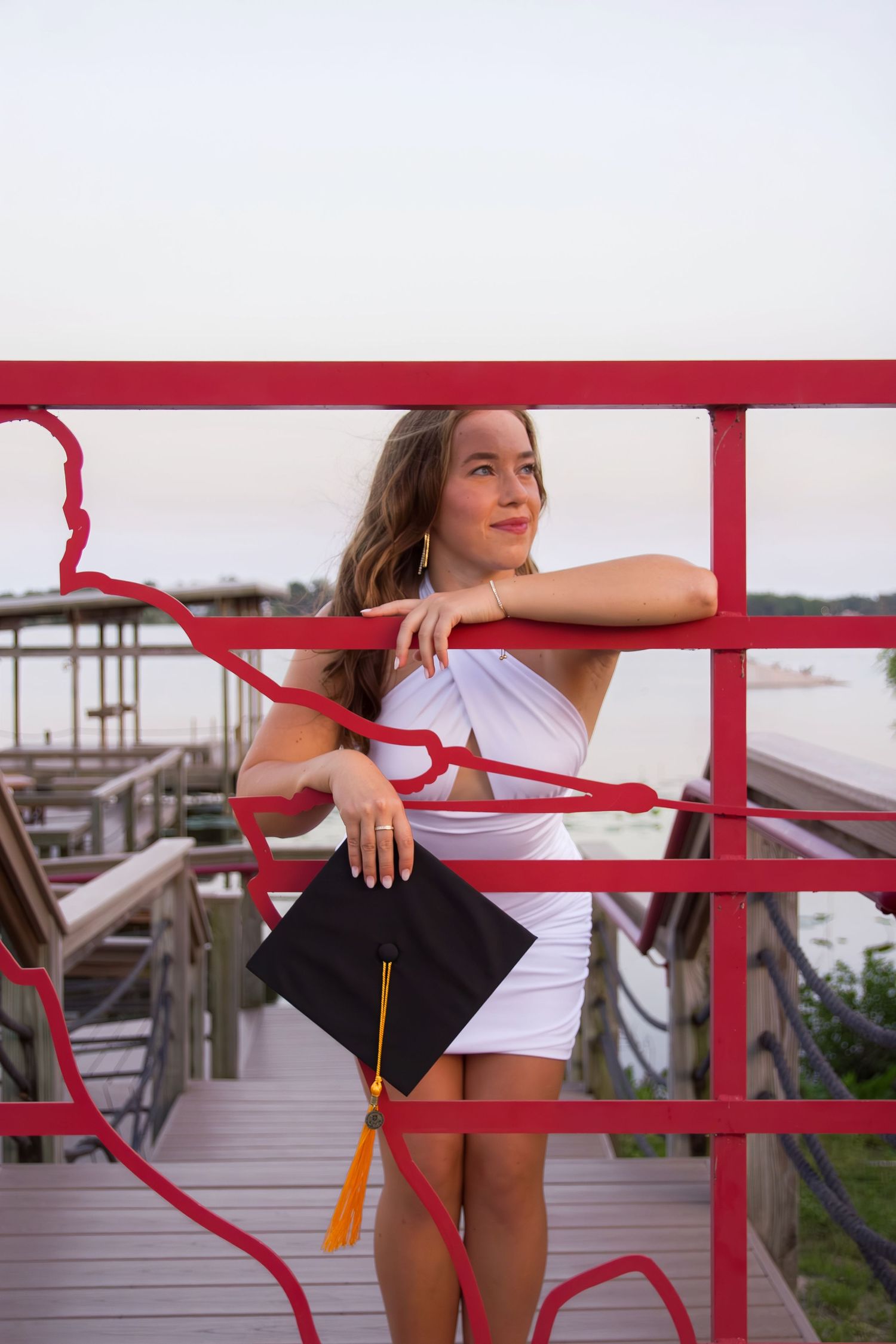 College campus photoshoot featuring a red railing and waterfront view.
