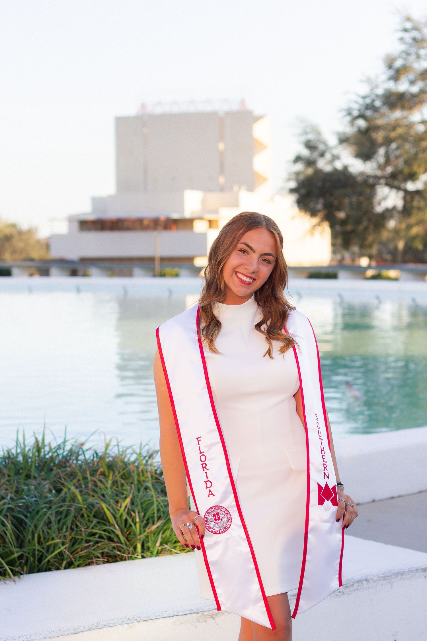 Person in white top with red stripes poses outdoors near water at sunset in multiple similar shots.