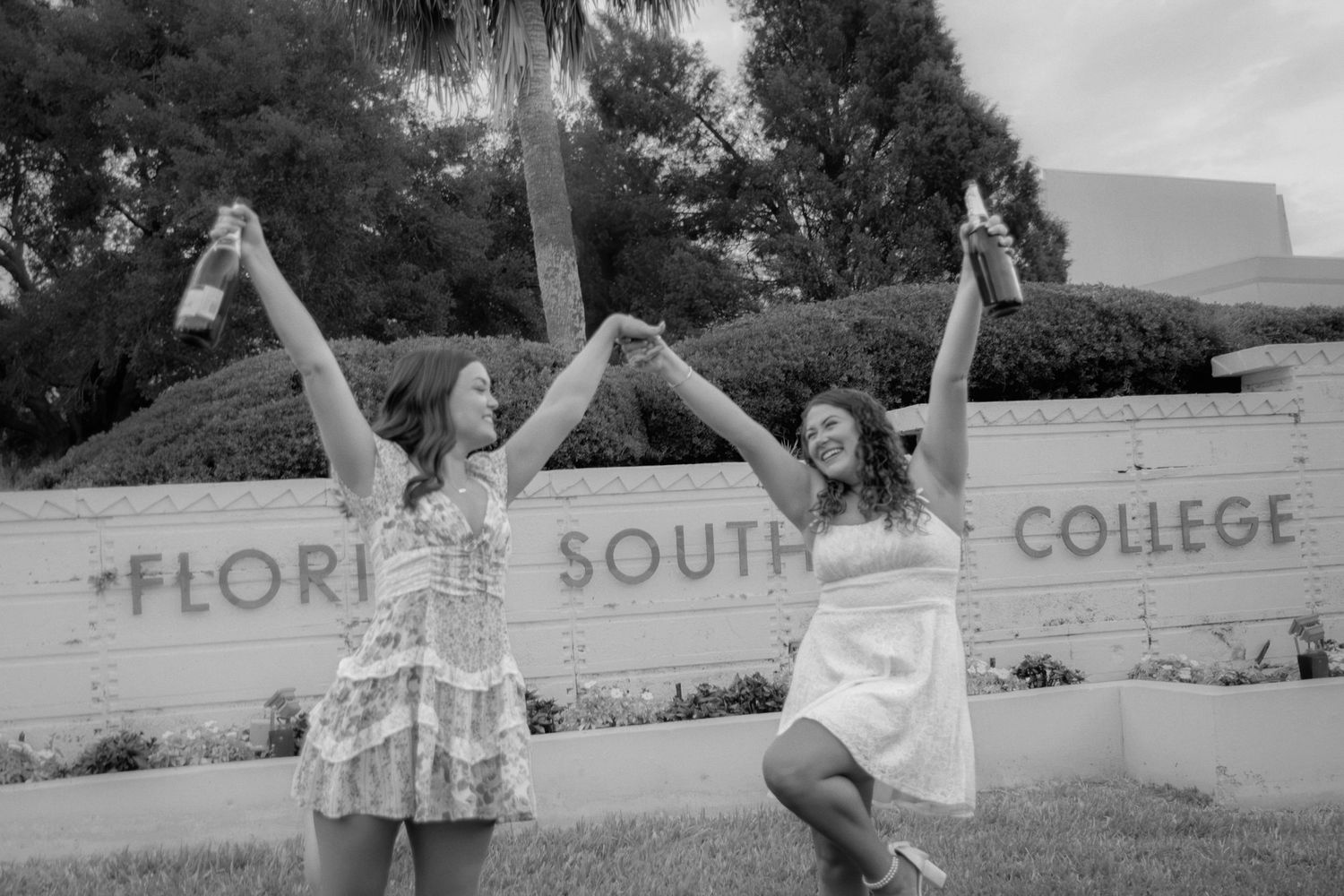 Group photo of graduates jumping in celebration in front of Florida Southern College sign.