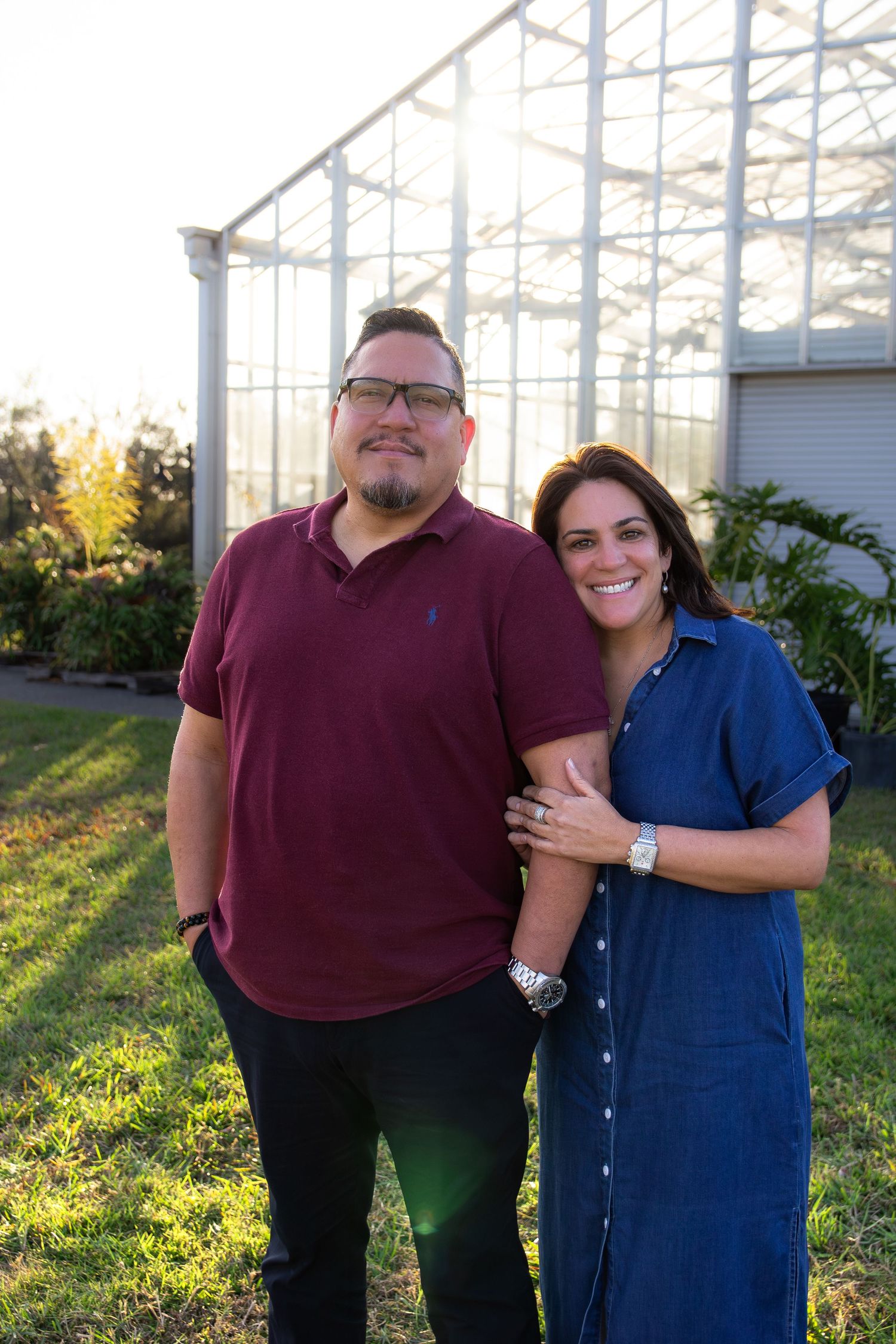 A couple shares a tender moment together outside a building with sunlit windows in the background.