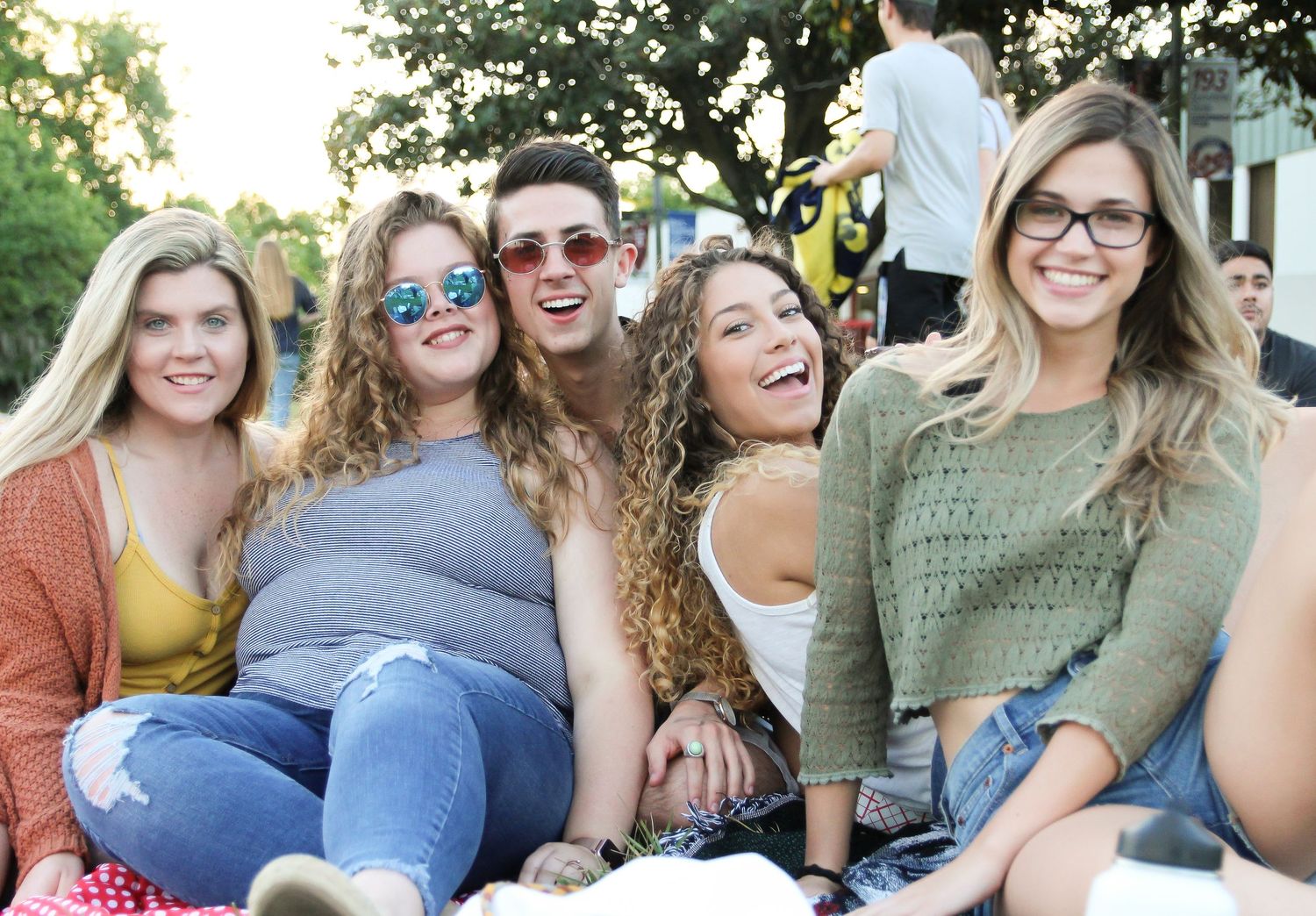Group of friends sitting outdoors together and smiling during a sunny afternoon gathering.