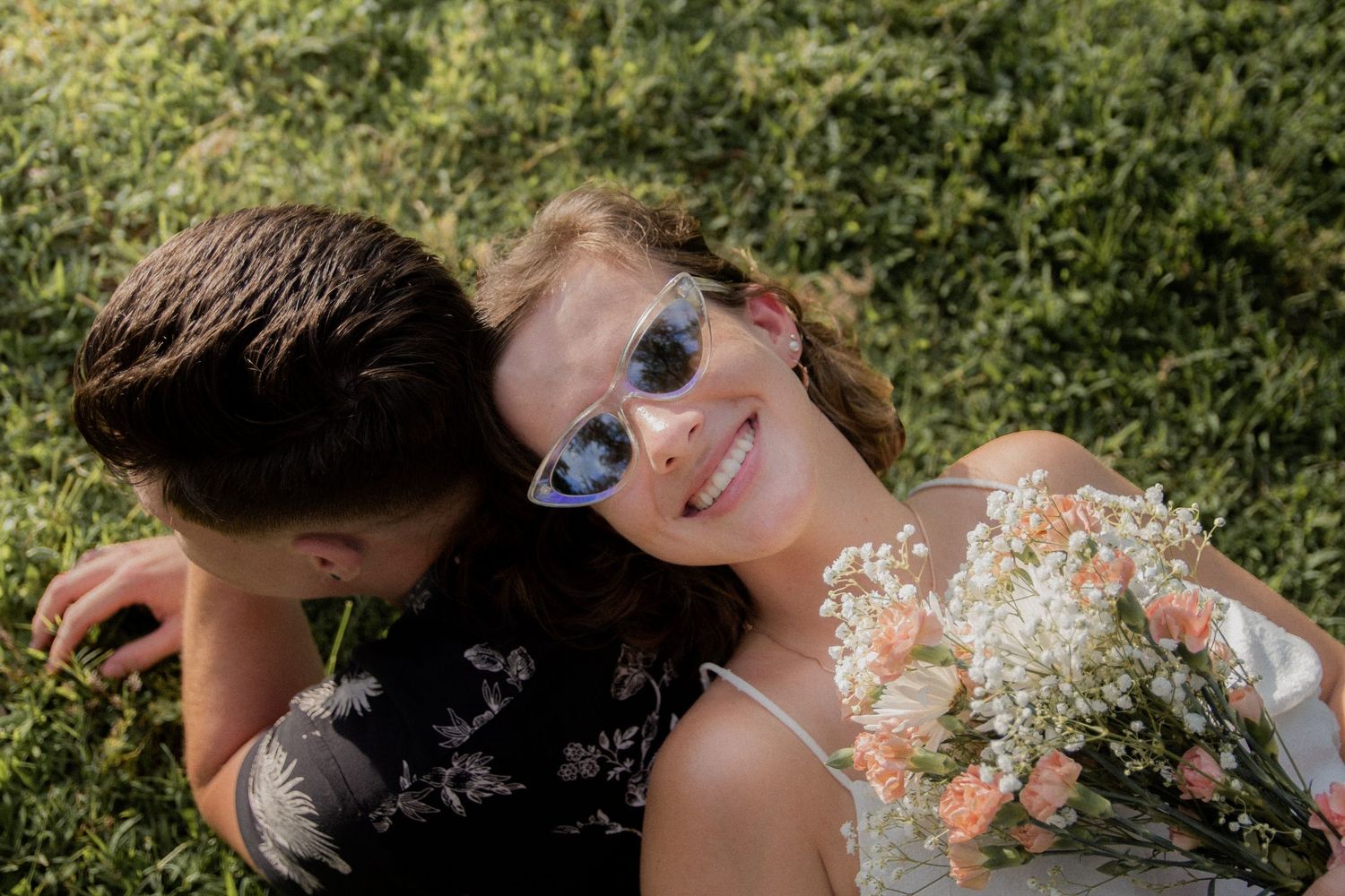 Romantic couple lying in grass during summer photoshoot.