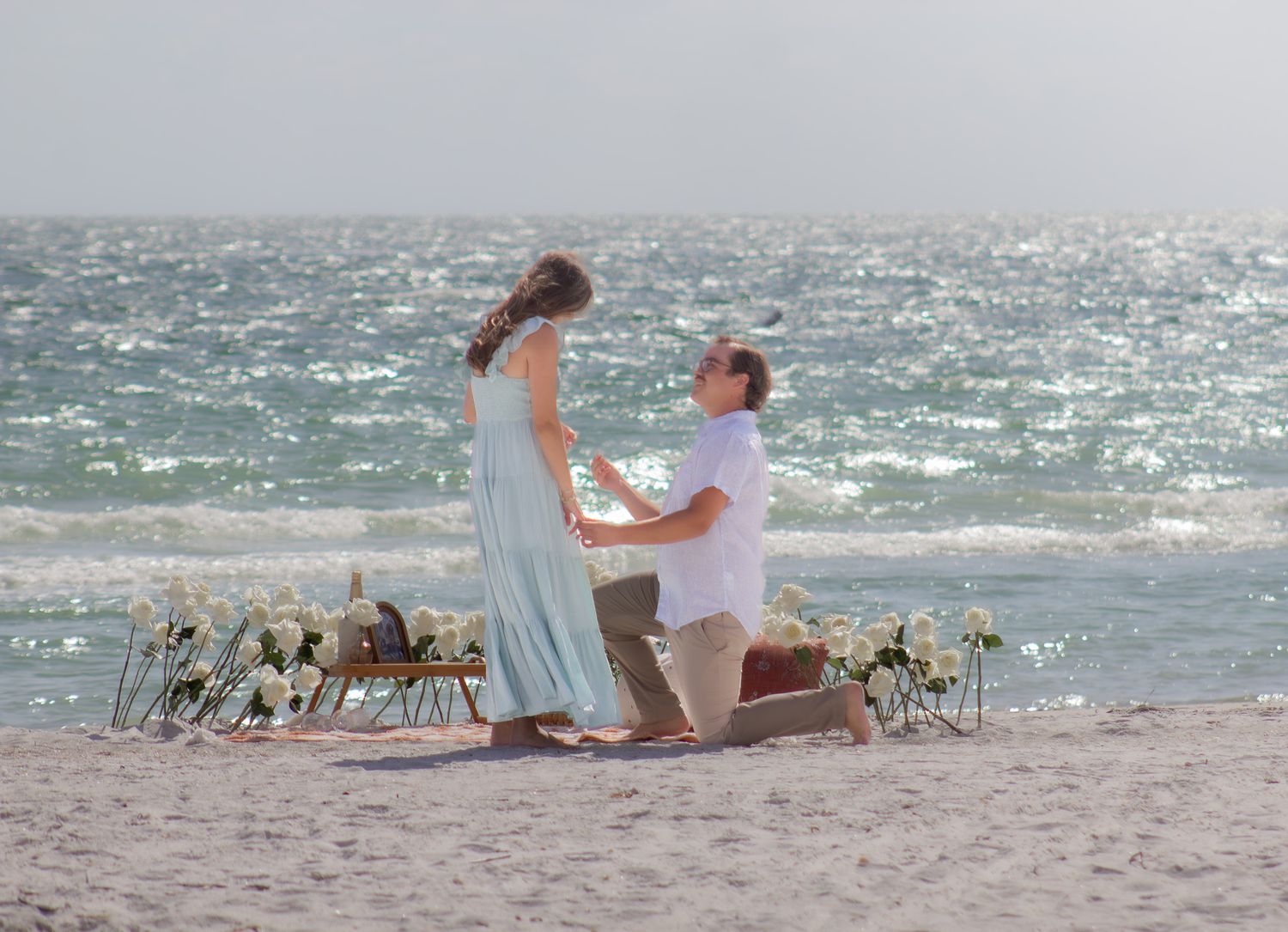 Beach proposal scene with decorative elements and couples silhouette against the ocean waves.
