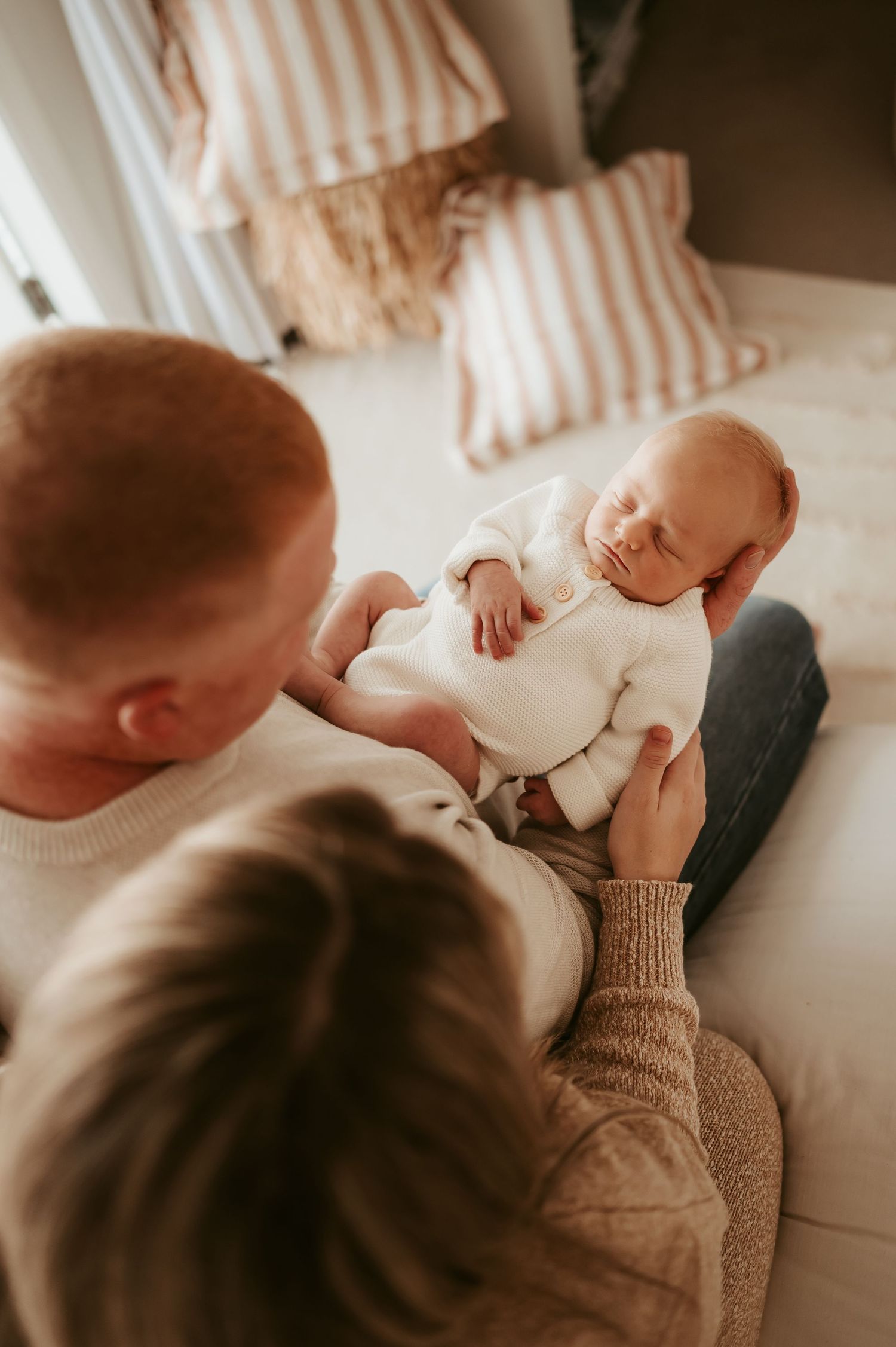 Intimate family moment captured from above on white bedding.