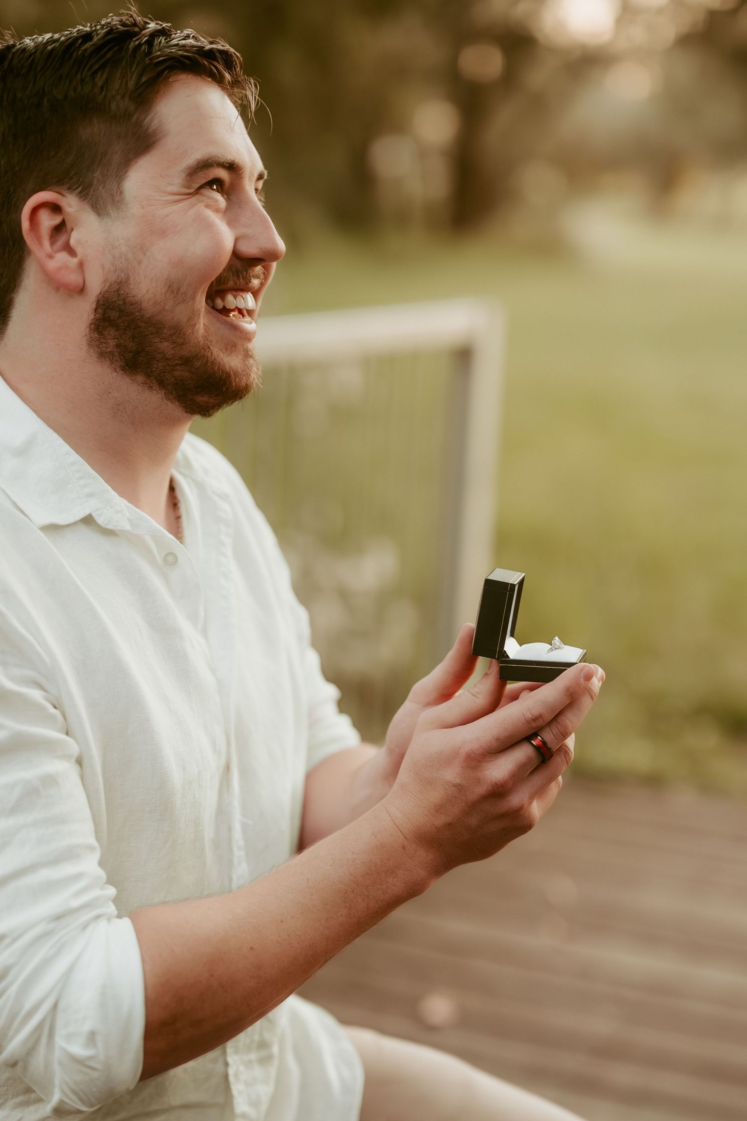 A close-up of someone holding a ring box during a proposal.