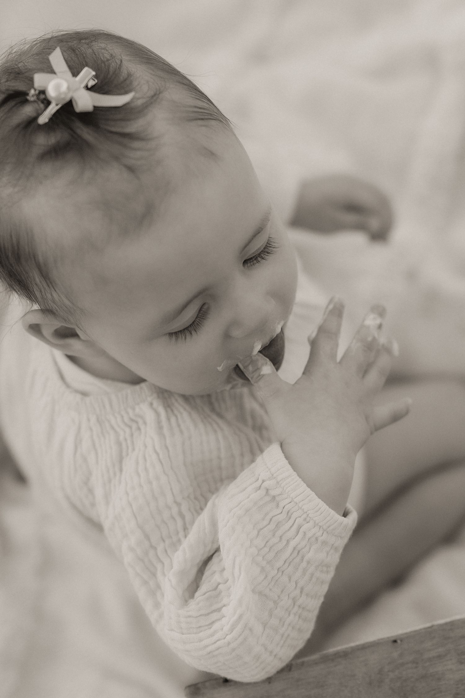 Dreamy black and white portraits capturing sweet moments of a cake smash with soft lighting.