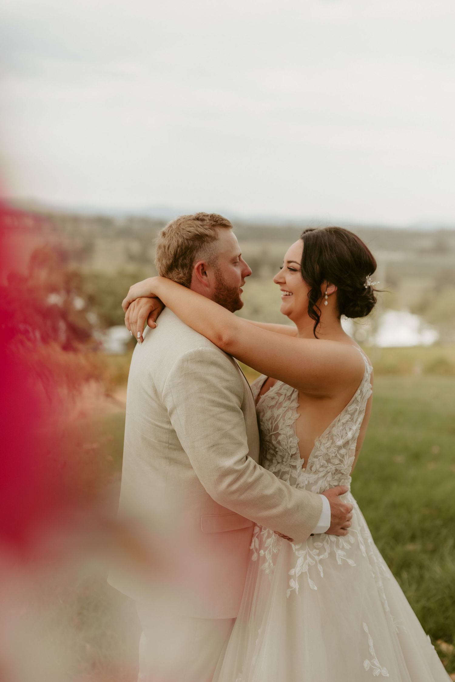 Romantic wedding couple embracing in an outdoor field during golden hour.