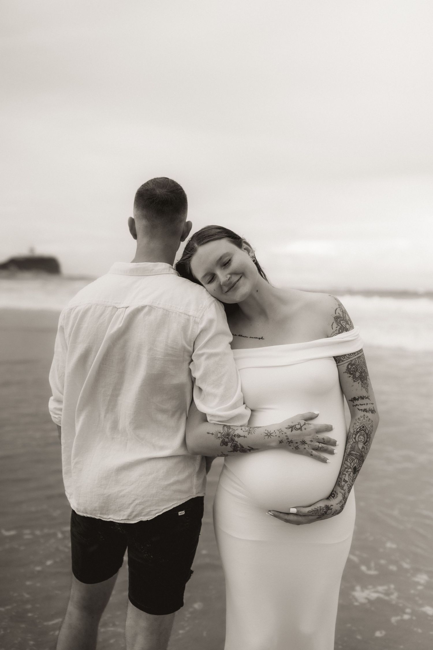 A couple shares intimate moments during a beach maternity photoshoot.