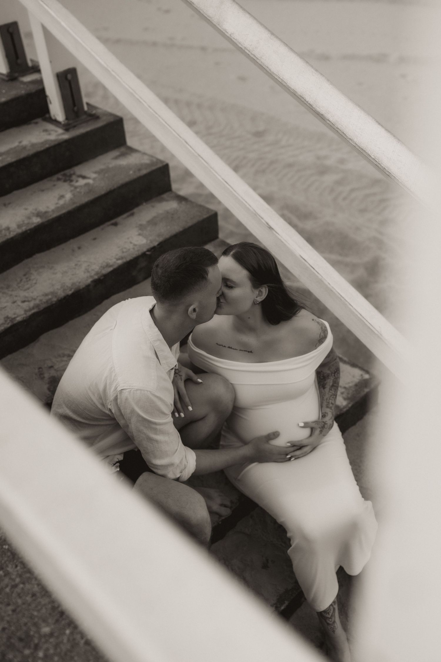 A romantic black and white photo series of a couple embracing on stairs.