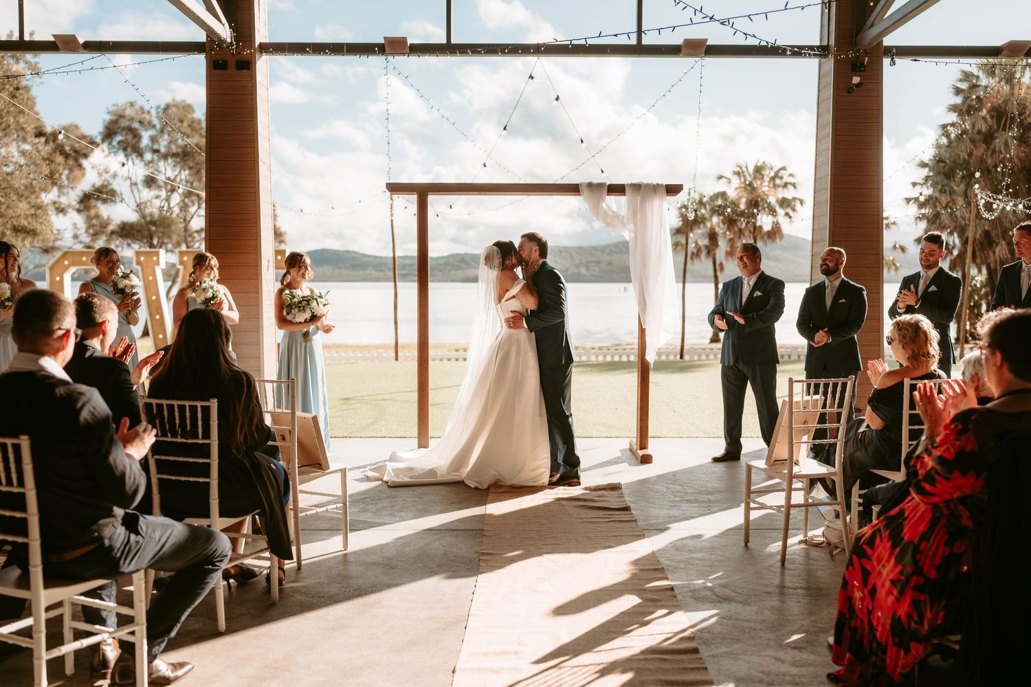 Wedding ceremony setup in an open-air pavilion with ocean views and natural lighting.