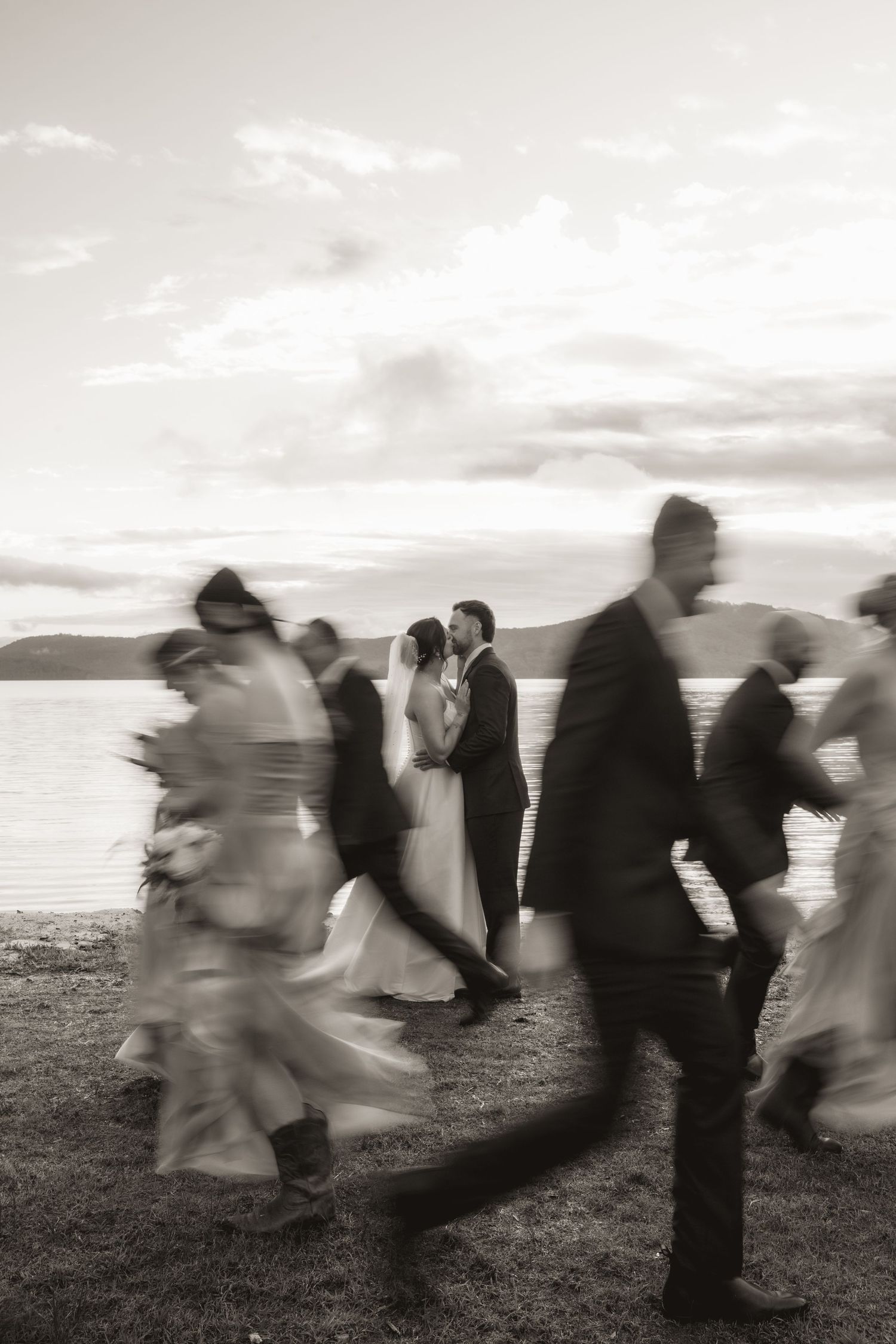 Motion blur photograph of wedding party dancing on beach at sunset.