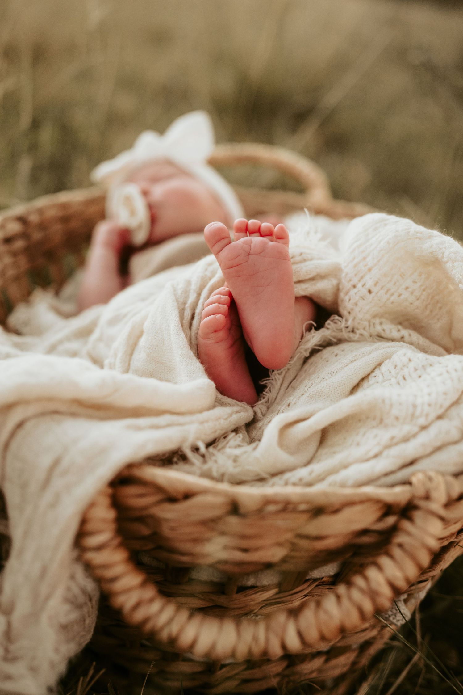 Tiny baby feet peeking out from soft cream-colored blankets in natural light.