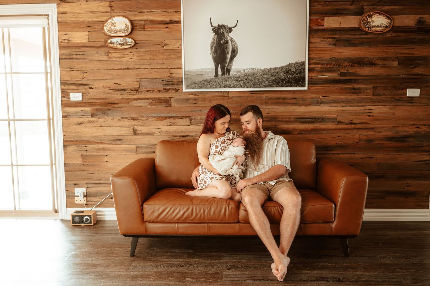 Modern living room interior with wooden walls and brown leather couch.