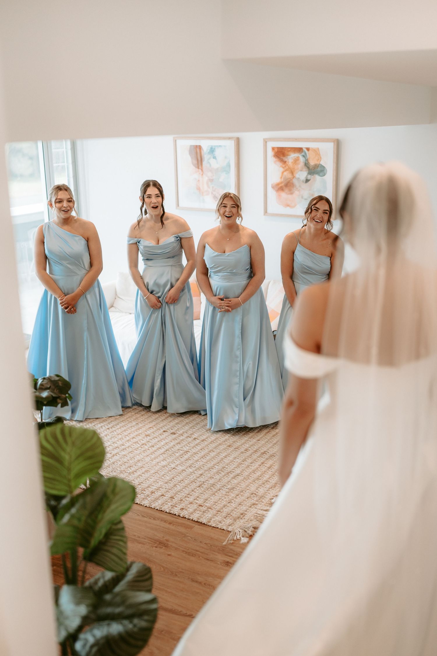 Bridesmaids in light blue dresses sharing an emotional first look with the bride.