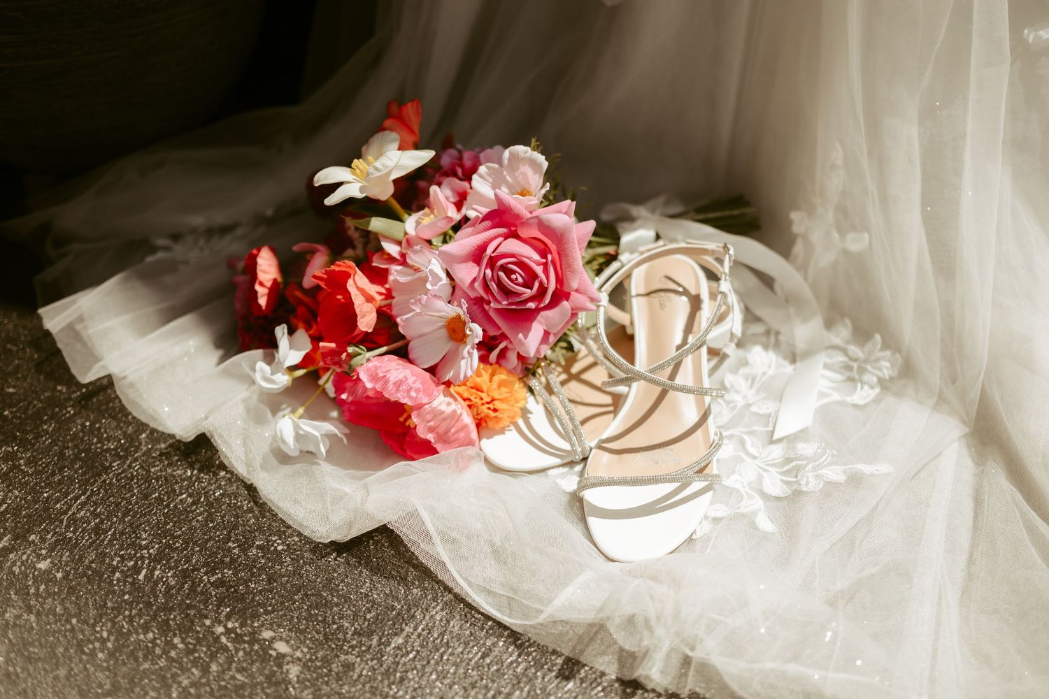 Close-up detail of white wedding dress fabric with pink floral decorative elements.