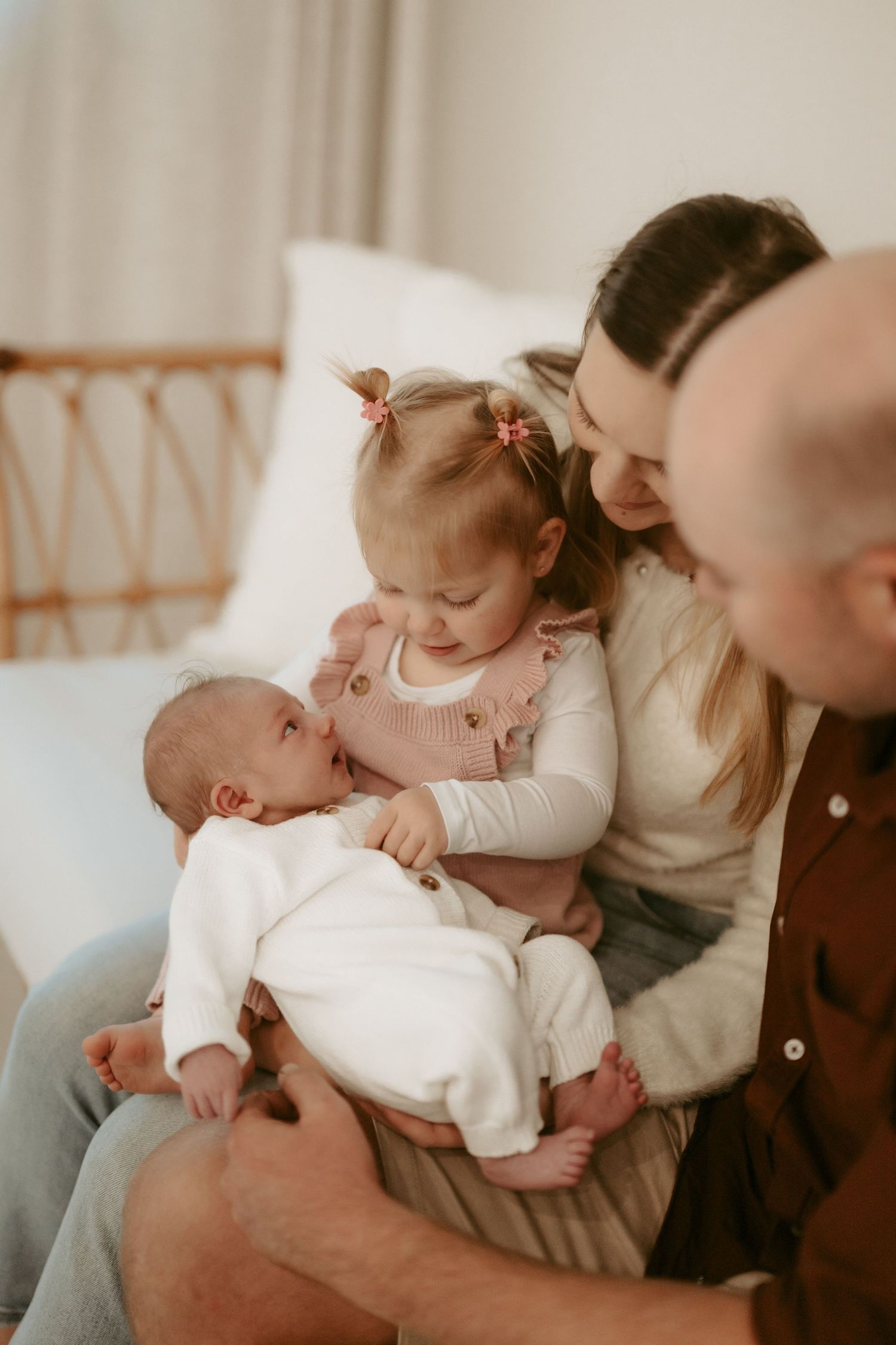 Tender family moment showing a baby being cradled and kissed in a softly lit indoor setting.